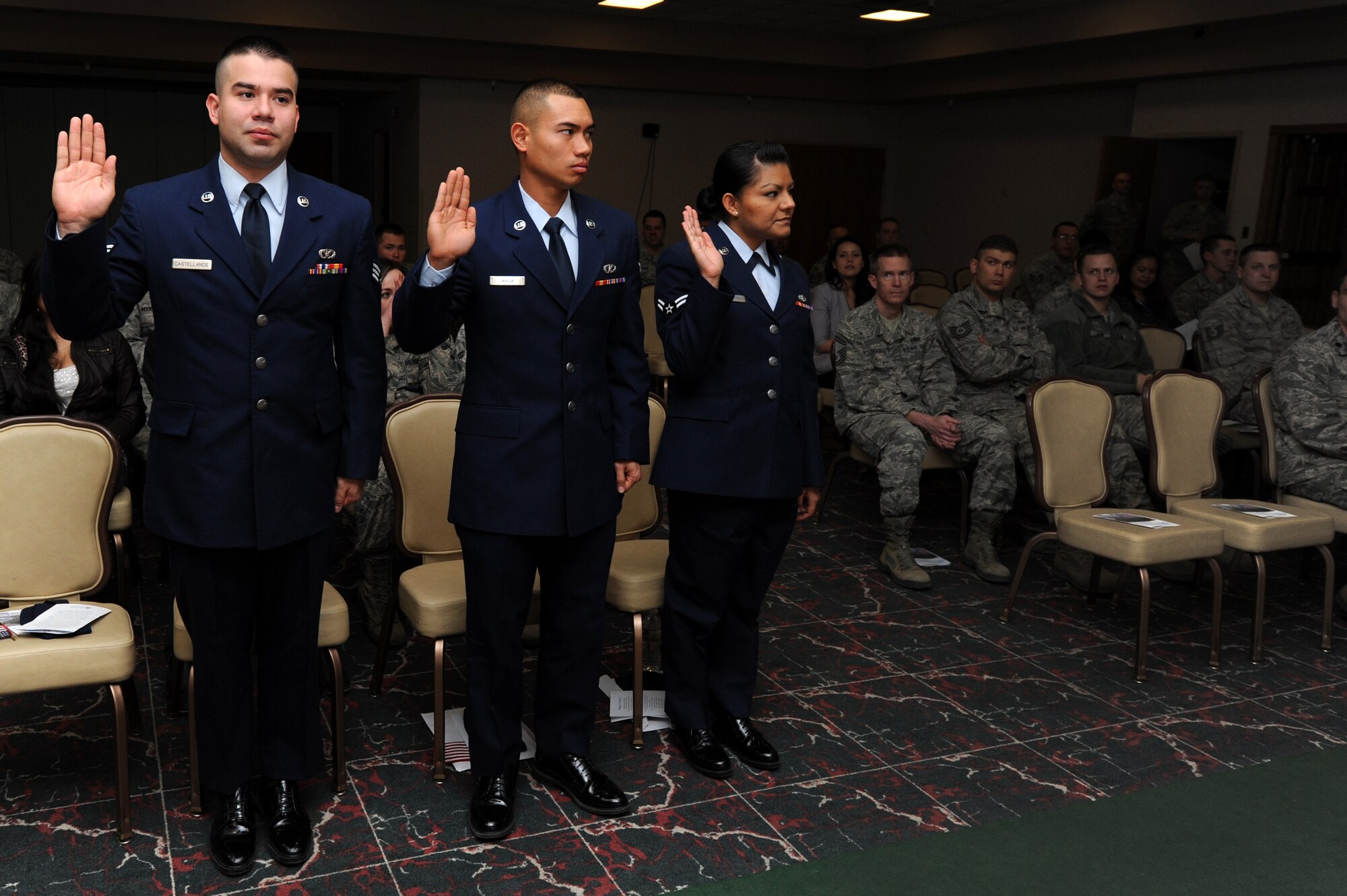 U.S. Air Force Airman 1st Class Fabio Castellanos and Airman 1st Class Mike Waga, 27th Special Operations Civil Engineer Squadron, and Airman 1st Class Maria Guerrero, 27th Special Operations Force Support Squadron, raise their hand as they are sworn in as American citizens at the Landing Zone at Cannon Air Force Base, N.M., Feb. 8, 2013.  After serving active duty for a year in the U.S. Air Force, the Airmen were able to apply for naturalization.  (U.S. Air Force photo/Senior Airman Jette Carr)