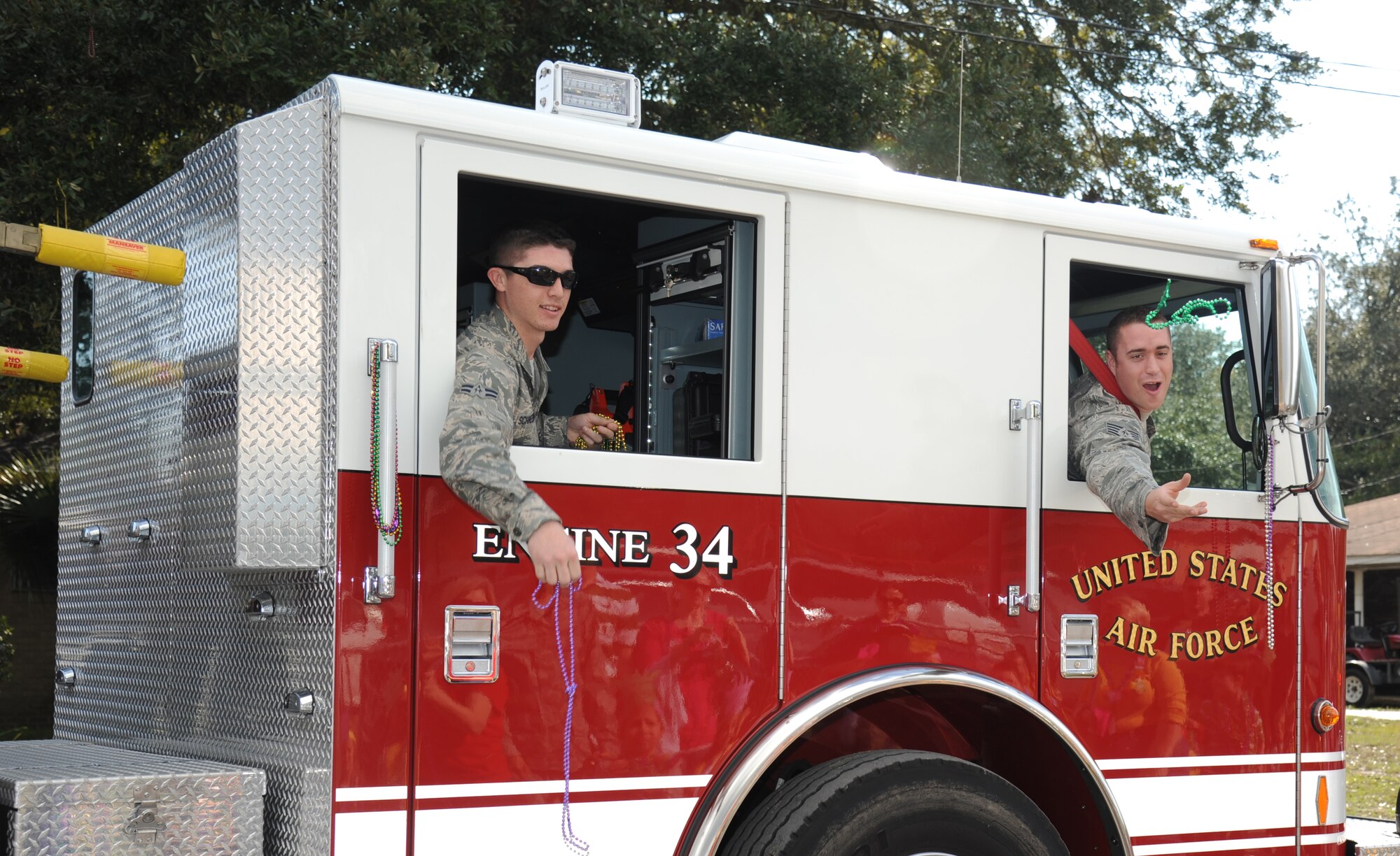 Staff Sgt. Nicholas Fasola and Airman 1st Class Aric Schneeberger, Keesler firefighters, throw beads during the Jeff Davis Elementary School Mardi Gras Parade in Biloxi, Miss., Feb. 8, 2013. The Keesler Honor Guard marched and Col. Mark Vivians, 81st Mission Support Group commander, and his wife, Lt. Col. Jileene Vivians, 2nd Air Force director of staff, served as grand marshals for the event.  (U.S. Air Force photo by Kemberly Groue)