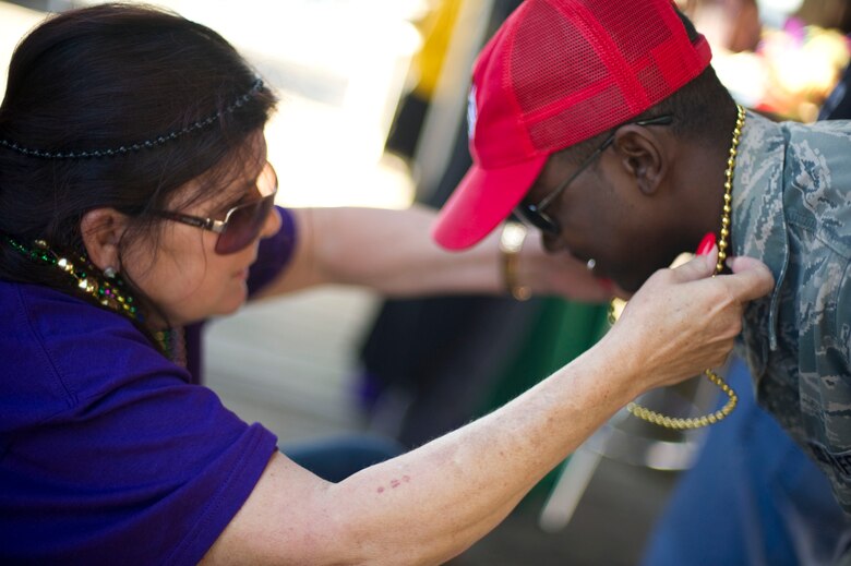 Senior Airman Lavelle Ali, 823rd RED HORSE, right, receives a bead necklace from a local resident after a mardi gras parade at Navarre Beach, Fla., Feb. 2, 2013. Hurlburt Field Airmen participated in the event to foster ties with the Emerald Coast community. (U.S. Air Force photo / Tech. Sgt. Vanessa Valentine)