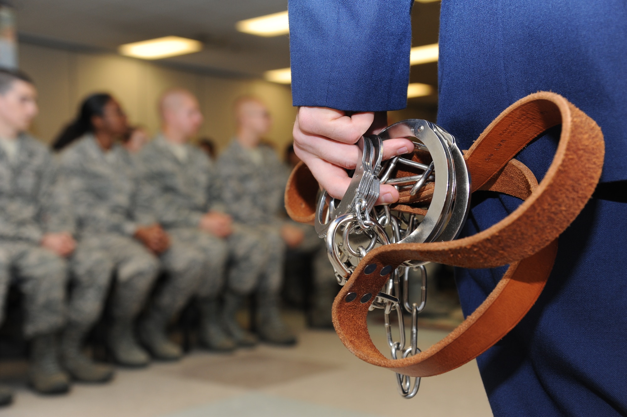 Staff Sgt. Christopher Vroman, 334th Training Squadron combat controller, stands ready with a pair of shackles in hand to place on the defendant following sentencing during a summary court martial Feb. 8, 2013, at the Levitow Training Support Facility, Keesler Air Force Base, Miss.  Mobile summary courts martial set an example for new Airmen about consequences of their actions by quickly imposing good order and discipline.  (U.S. Air Force photo by Kemberly Groue)