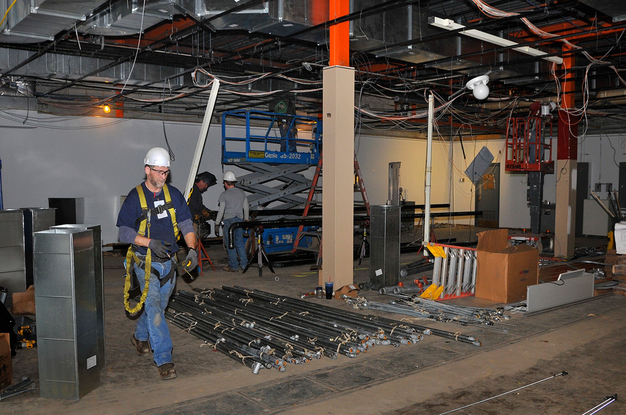 From left, Robert Flanders, with subcontractor Tri-State Sprinkler Corp., works to install a sprinkler system while David Benson and son David with subcontractor Billy Thomas Plumbing and Electric Service, install chilled water piping for HVAC units during the renovation of the Precision Measurement Equipment Laboratory at AEDC. (Photo by Jacqueline Cowan)