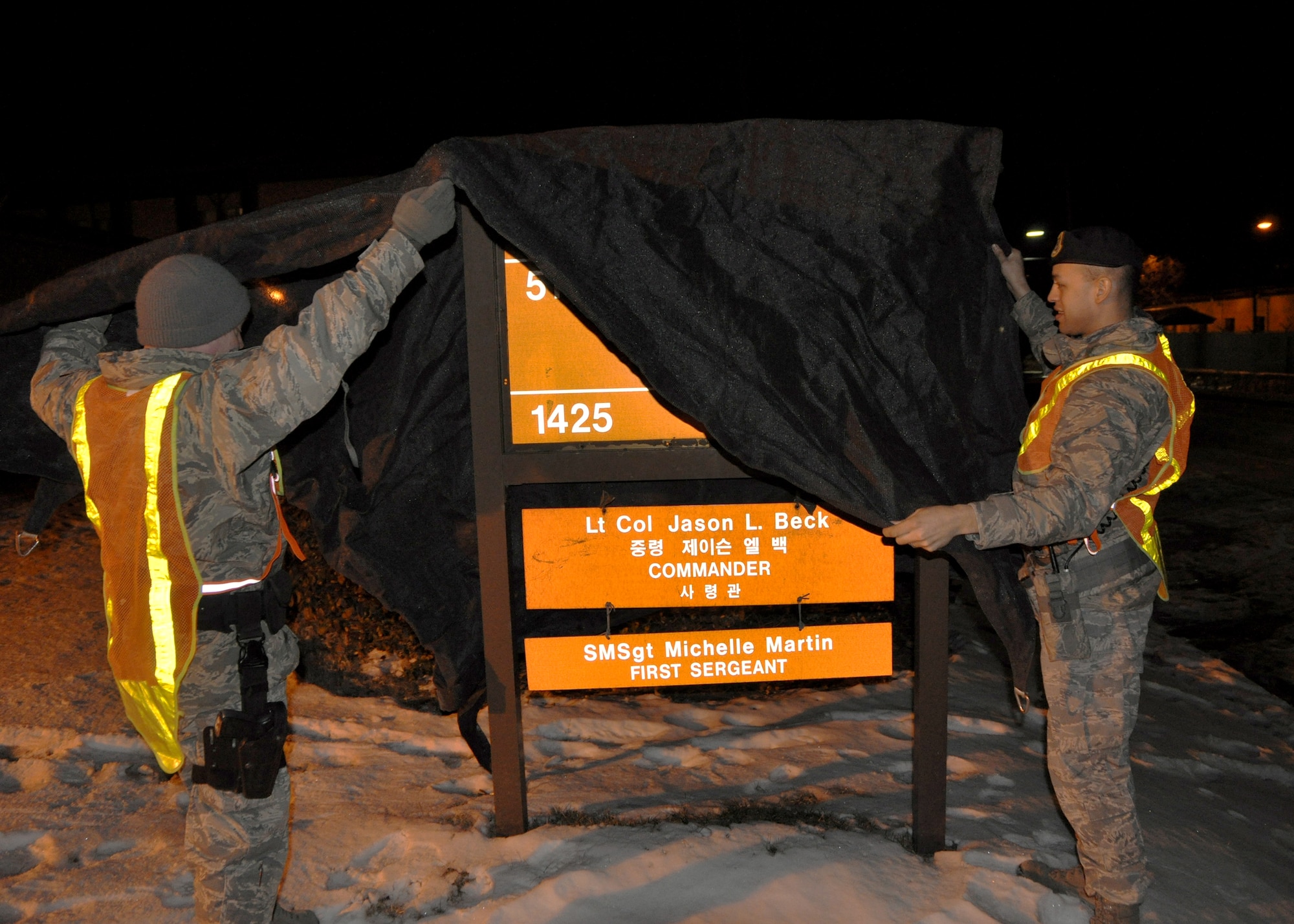 Tech. Sgt. Brandon Snider, 51st Security Forces Squadron flight chief, and Staff Sgt. Jason Baldridge, base defense operations center controller, cover the sign outside of building 1425 for operational readiness exercise Beverly Bulldog 13-02, Feb. 11, 2013. Throughout the week, the Airmen will be tested on their ability to utilize their chemical, biological, radiological and nuclear training, as well as administer self-aid and buddy-care during a contingency.  (U.S. Air Force photo/Senior Airman Kristina Overton)
