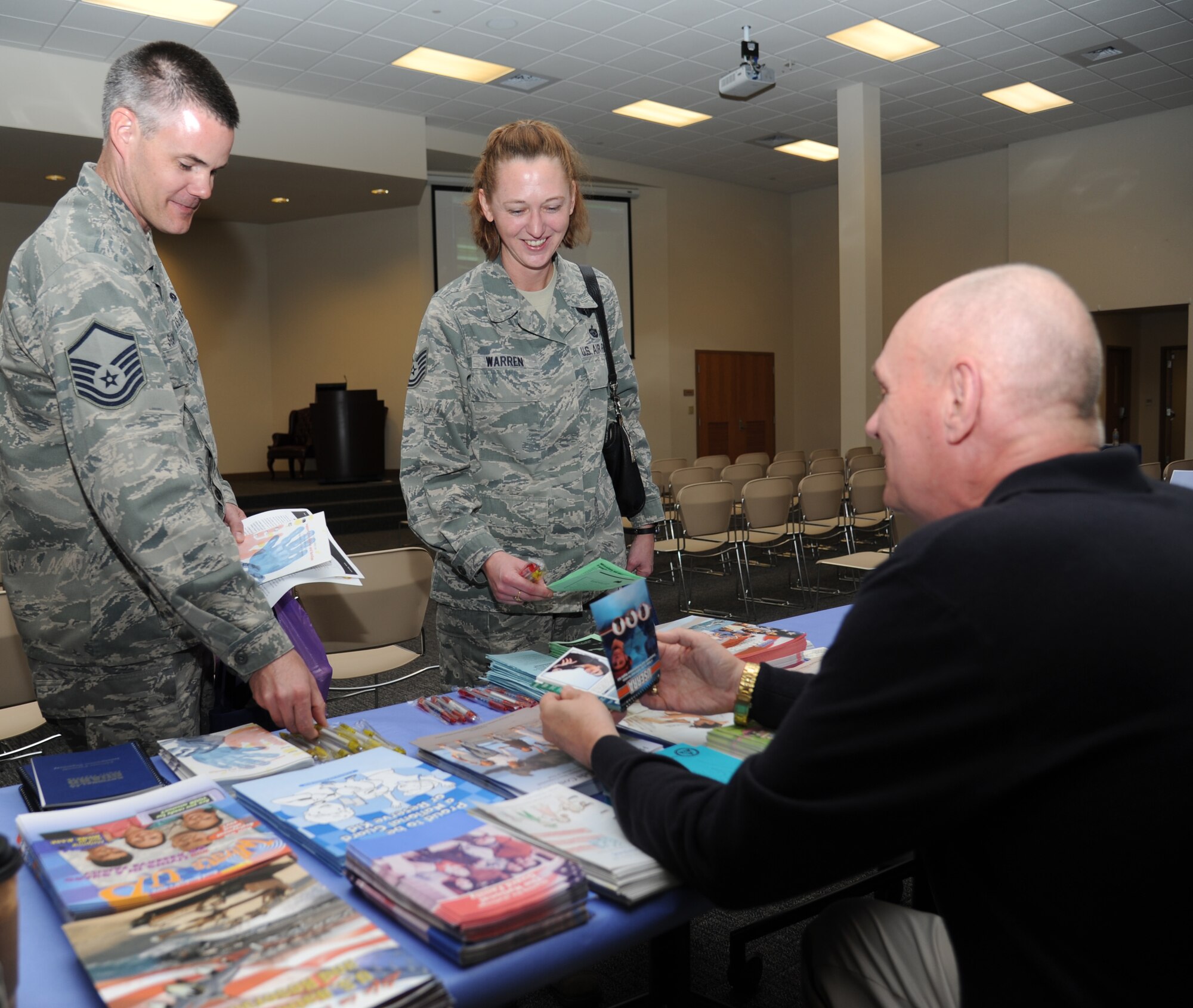 Master Sgt. Scott Sigworth, 403rd Maintenance Squadron, and Tech. Sgt. Jennifer Warren, 81st Training Wing, receive literature from retired Chief Master Sgt. Charles Carrigan, Gulfport Mississippi Air National Guard Airman and Family Readiness program manager, on various support programs offered during the military preparedness exposition Feb. 7, 2013, at the Roberts Consolidated Aircraft Maintenance Facility.  Various agencies set up information displays and booths to assist those who have recently returned from a deployment or will soon be deploying.  (U.S. Air Force photo by Kemberly Groue)