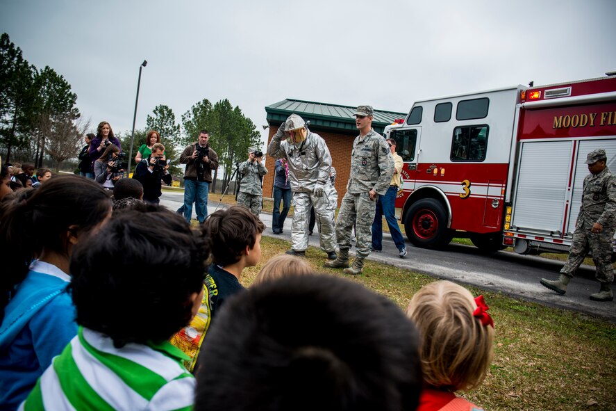 U.S. Air Force Tech. Sgt. Eric Kunzman (fire suit), former 23d Civil Engineer Squadron firefighter, and Staff Sgt. Jonathon Flacker, 23d CES firefighter crew chief, interact with Sallas Mahone Elementary School first graders Feb. 8, 2013, in Valdosta, Ga. Kunzman returned from a year-long tour to Osan Air Base, Korea, and surprised his son at school when he was asked to pull back the visor of the unknown firefighter. (U.S. Air Force photo by Staff Sgt. Jamal D. Sutter/Released)