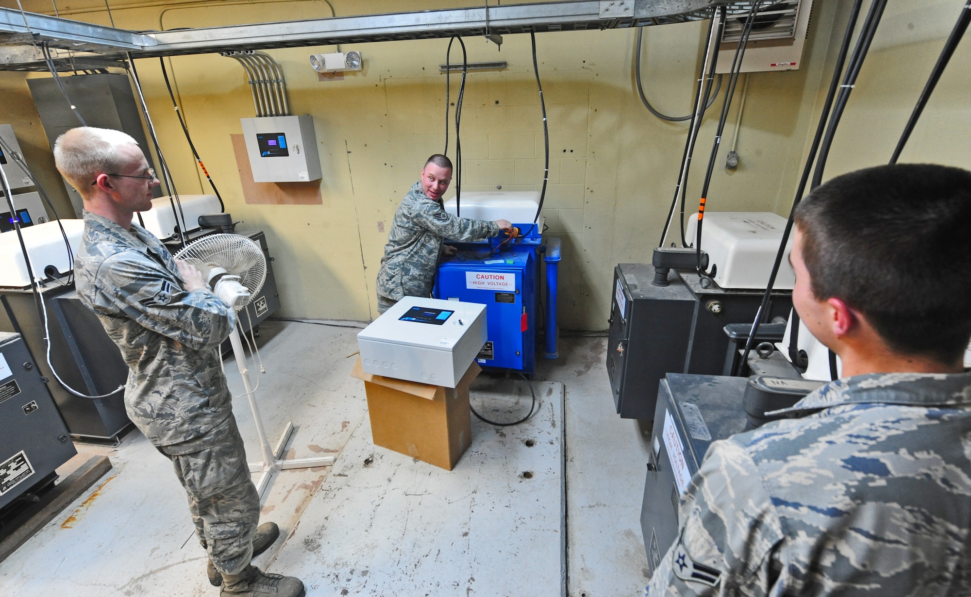 WHITEMAN AIR FORCE BASE, Mo. -- Staff Sgt. Clint Smith, 509th Civil Engineer Squadron electrical systems craftsman, trains Airman 1st Class Henry Fox, and Airman 1st Class Devin Laird, both 509th CES electrical systems apprentices, on maintaining oil filled regulators, Jan. 29. The regulators provide electrical power to various electrical systems on the flightline. (U.S. Air Force photo/Staff Sgt. Nick Wilson) (Released)