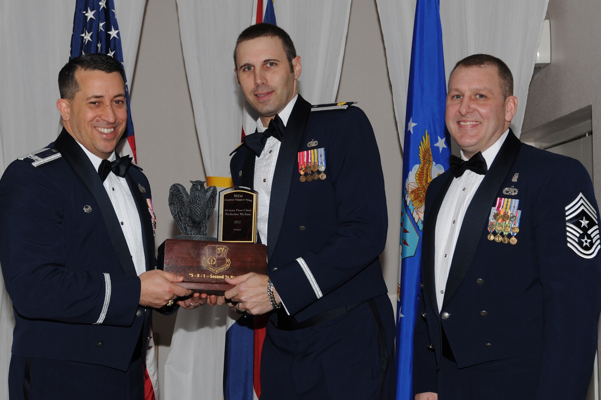 RAF CROUGHTON, United Kingdom – Maj. Erik Dutkiewicz, 423rd Security Forces Squadron commander, accepts the 501st Combat Support Wing’s Airman of the Year of the Year award on behalf of Airman 1st Class Nicholas Mylius, 423rd SFS, during the 501st CSW Annual Awards at RAF Croughton Feb. 8. Mylius, from Yuma, Ariz., was handpicked to attend the Capitol Hill Summit, where he represented the wing's enlisted corps. He also volunteered at the Manor School where he passed on lessens to at-risk United Kingdom teens; the program was recognized by the Royal Family. (U.S. Air Force photo by Tech. Sgt. Chrissy Best)