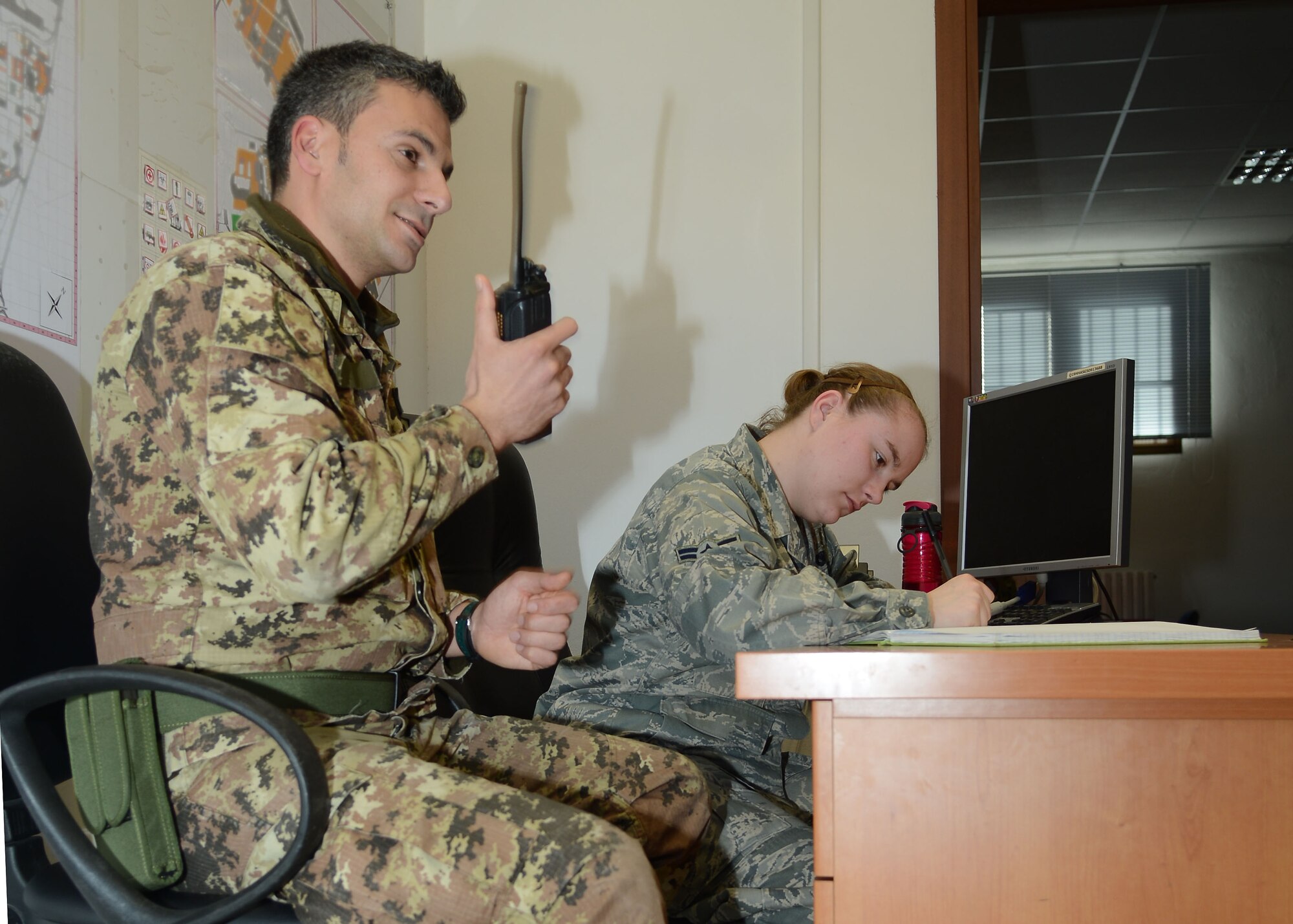Italian air force Sgt. Marco Gallo works with and Airman 1st Class Christina Naples, 31st Security Forces Squadron, Jan. 29, 2013, in the Consolidated Operations Desk on Aviano Air Base, Italy.  The COD helps the 31st SFS and the Italian air force effectively communicate and share critical information on base.  (U.S. Air Force photo / Senior Airman Jessica Hines)