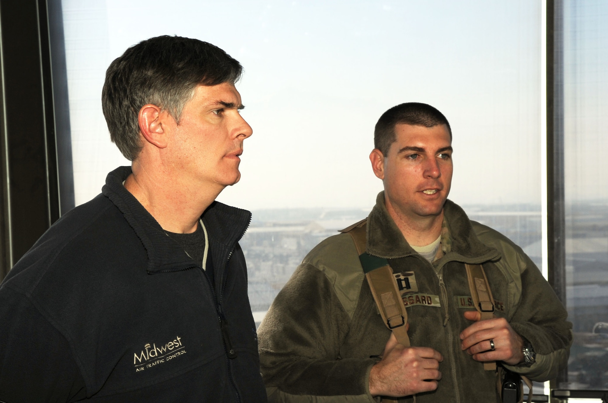 Capt. Christopher Lessard, 455th EOSS Airfield Operations Liaison Officers, speaks with Shelby Strunk, training standardization manager for Midwest Air Traffic Control, in the air traffic control tower on Bagram Airfield, Afghanistan, Feb. 8, 2013. Due to stipulations in the Status of Forces Agreement between the United States and Afghanistan, the day-to-day operation of the airfield is conducted by contracted employees. (U.S. Air Force photo/Staff Sgt. David Dobrydney)