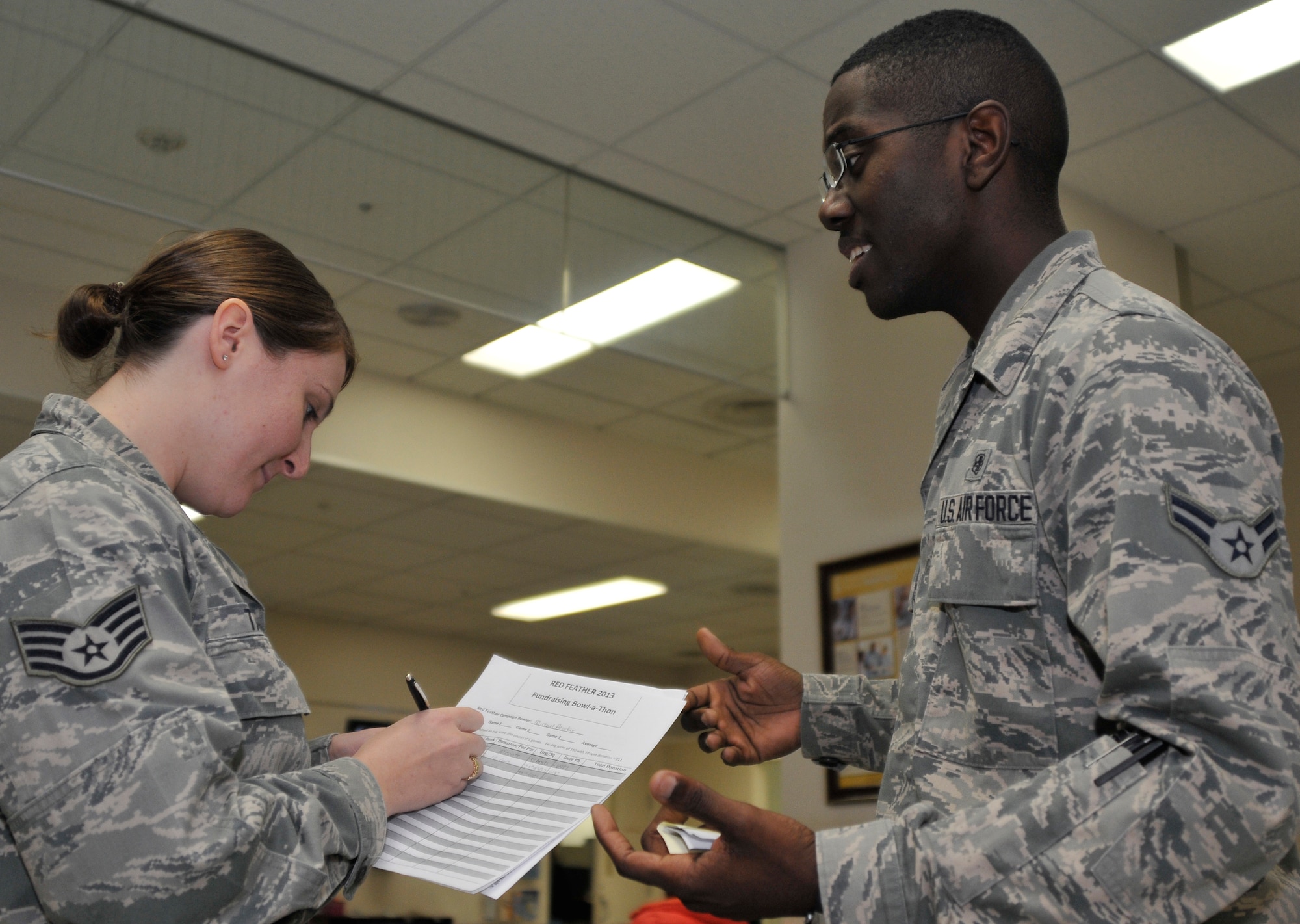 U.S. Air Force Staff Sgt. Sarah Taber, 35th Medical Group Family Health Clinic NCO in charge, writes down her donation for the Red Feather Bowlathon as Airman 1st Class Michael Blocker, 35 MDG Public Health technician, explains the significance of the Red Feather Campaign at Misawa Air Base, Japan, Feb. 6, 2013. The bowlathon is a fun way for people to participate and help raise money for the Misawa community. The Red Feather Campaign is a Japanese charitable program that supports local social welfare programs. (U.S. Air Force photo by Tech. Sgt. Phillip Butterfield)