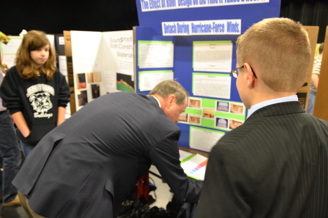 Bill Ryals closely examines the materials presented by the eventual overall science fair winner. 