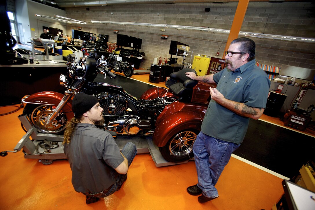 Jon Arnn (left), a mechanic and Jeff Myers a salesman for New River Harley Davidson discuss the Kliktronic electronic gear actuator and other aspects of recently retired Sgt. Maj. Raymond H. Mackeyâ€™s custom Tri-Glide on Dec. 11. 2012, in Jacksonville N.C. Mackey, who is currently attached to Wounded Warrior Battalion, who has ridden motorcycles for more than 35 years, lost his legs in an improvised explosive device accident while serving with 3rd Battalion 10th Marine Regiment, in Helmand province Afghanistan in 2009.