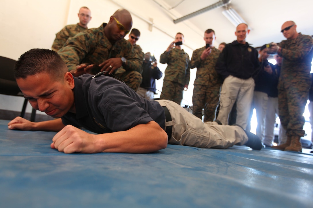 Reynaldo S. Ortiz, a police officer for the Provost Marshal Office here, is stunned during training at Del Mar’s old fire house here Feb. 12.  The Taser has recently been added to Camp Pendleton’s force continuum. Police officers and military police here are undergoing training to learn how to effectively, properly and safely employ the Taser.