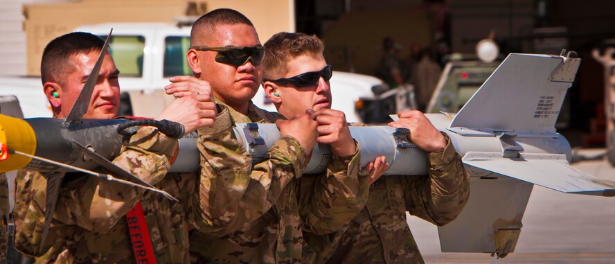 KANDAHAR AIRFIELD, Afghanistan --(From left to right) Staff Sgt. William Bernhardt, Senior Airman Kameran Fernandez and Senior Airman Matthew Furey, all 451st Expeditionary Aircraft Maintenance Squadron, Weapons Load Crew #07, carry an AIM-9M missile during a weapons load competition here Feb. 11. Bernhardt and two other Airmen made up a three-man weapons load crew and completed a four-phase evaluation. Their overall score will be put up against other scores of weapons load crews from their home station, Shaw Air Force Base, S.C. (U.S. Air Force photo/Senior Airman Scott Saldukas)