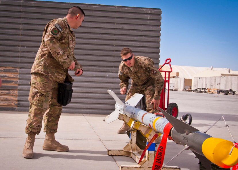 KANDAHAR AIRFIELD, Afghanistan -- (From left to right) Staff Sgt. William Bernhardt and Senior Airman Matthew Furey, both 451st Expeditionary Aircraft Maintenance Squadron weapons loaders, inspect an AIM-9M missile during a weapons load competition here Feb. 11. The two Airmen were a part of a three-man weapons loading crew and completed a four-phase evaluation. Their overall score will be put up against other scores of weapons load crews from their home station, Shaw Air Force Base, S.C.   (U.S. Air Force photo/Senior Airman Scott Saldukas)