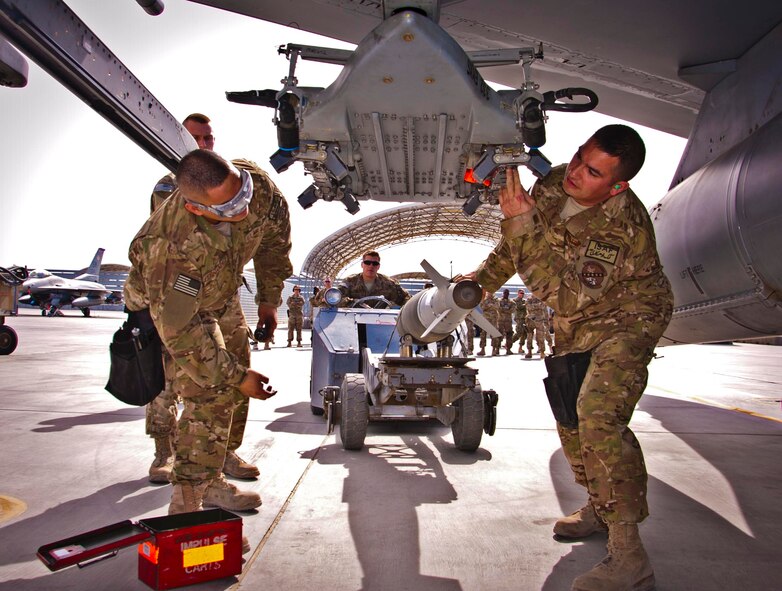 KANDAHAR AIRFIELD, Afghanistan -- – (From left to right) Senior Airman Kameran Fernandez, from Maui, Hawaii, Senior Airman Matthew Furey, from Mente Vista, and Staff Sgt. William Bernhardt, from Valdosta, Ga., Calif., load a GBU-38 bomb during a weapons load competition  here Feb. 11. The three-man crew completed four separate phases of the competition and their overall score will compete against other weapons load crews’ scores back at their home station, Shaw Air Force Base, S.C. (U.S. Air Force photo/Senior Airman Scott Saldukas)