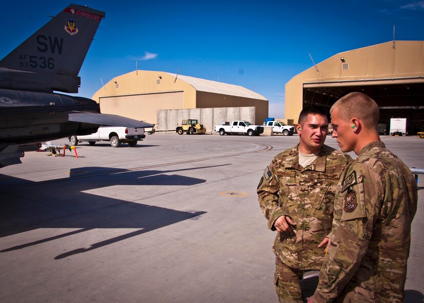 KANDAHAR AIRFIELD, Afghanistan -- Staff Sgt. William Bernhardt, 451st Expeditionary Aircraft Maintenance Squadron weapons load crew chief, talks to a weapon loading competition evaluator here Feb. 11. Bernhardt and two other Airmen made up a three-man weapons loading crew and completed a four-phase evaluation. Their overall score will be put up against other scores of weapons load crews from their home station, Shaw Air Force Base, S.C. (U.S. Air Force photo/Senior Airman Scott Saldukas)