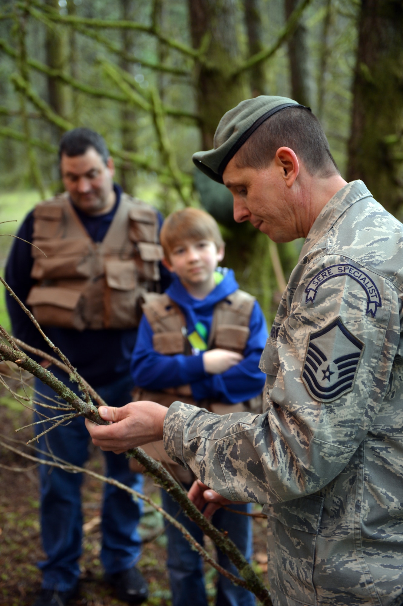 Master Sgt. Charles Pfennig, 62nd Operations Support Squadron, survival, evasion, resistance and escape specialist, talks to Carl Hess and his stepfather, James Sullivan, about the different sizes of wood needed to light a fire Feb. 11, 2013, at Joint Base Lewis-McChord, Wash. SERE specialists teach these same techniques to military members serving around the world. (U.S. Air Force photo/Staff Sgt. Jason Truskowski)