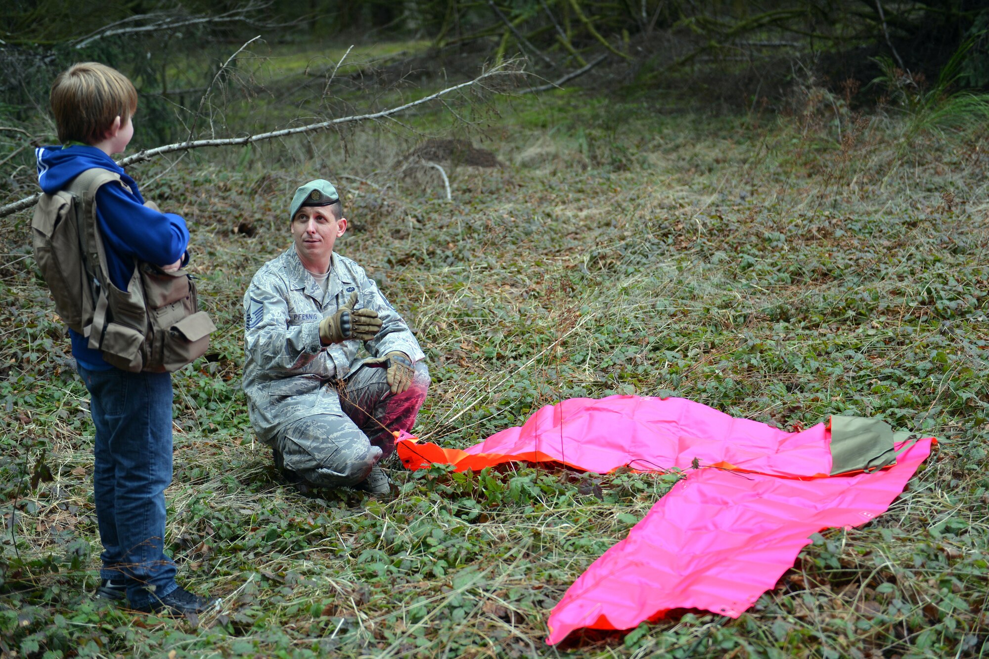 Master Sgt. Charles Pfennig, 62nd Operations Support Squadron, survival, evasion, resistance and escape specialist, teaches Carl Hess how to lay out proper distress signals Feb. 11, 2013, at Joint Base Lewis-McChord, Wash. Pfennig showed Carl the different materials that can be used and explained what the signals meant. (U.S. Air Force photo/Staff Sgt. Jason Truskowski)