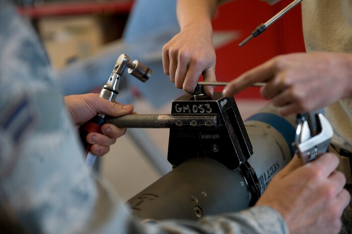 Airman 1st Class Matthew Porto, 57th Maintenance Squadron munitions systems apprentice, and Staff Sgt. Brittney Benke, 57th Maintenance Squadron munitions systems craftsman, torque the coupling ring on a CATM 9M Feb. 7, 2013, Nellis Air Force Base, Nev. The coupling ring attaches the guidance unit to the missile body assembly. (U.S. Air Force photo by Tech. Sgt. Taylor Worley)