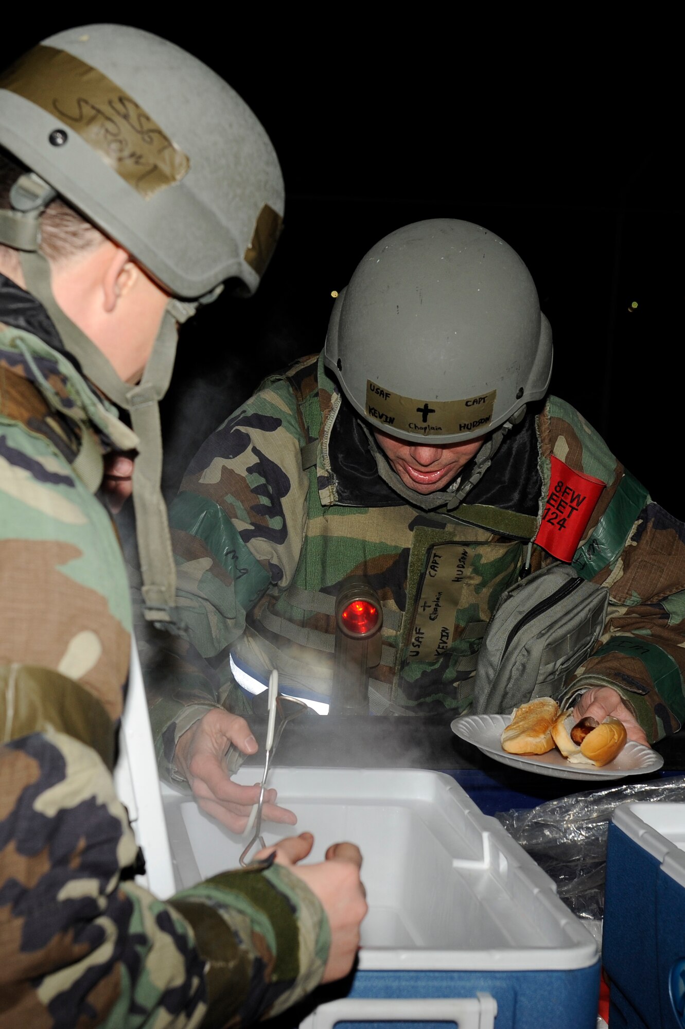 Staff Sgt. Joshua Strom, left, 8th Fighter Wing chaplain assistant, and Capt. Kevin Hudson, 8th FW Chaplain, serve hot dogs to the Airmen working out in the cold weather during exercise Beverly Bulldog 13-2 at Kunsan Air Base, Republic of Korea, Feb. 12, 2013. Visiting with the Airmen allows the Chaplain to help boost morale and to give them support and guidance through the exercise. (U.S. Air Force photo by Senior Airman Marcus Morris/Released)
