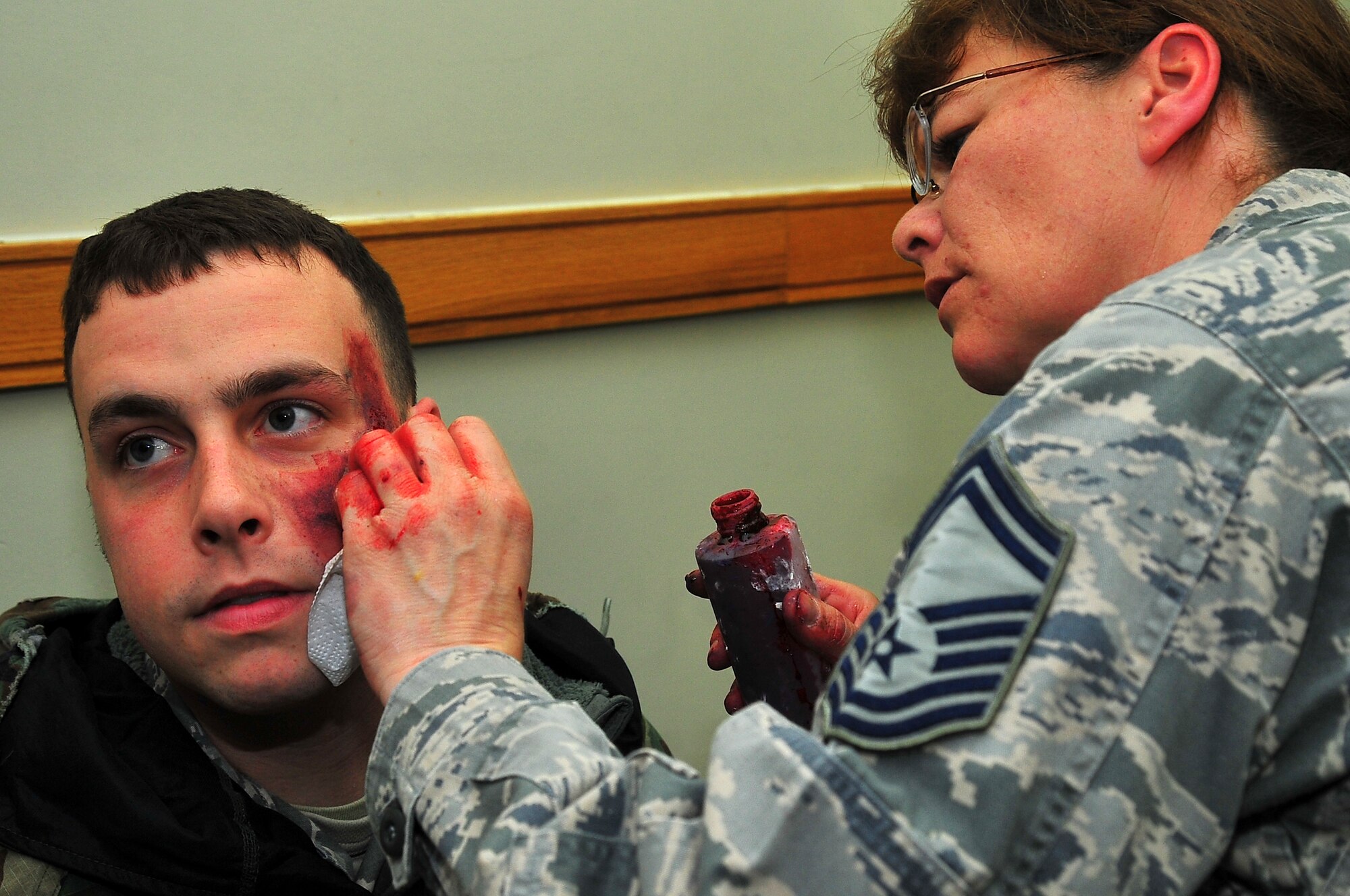 Senior Master Sgt. Tracey House, 51st Medical Support Squadron Superintendent, applies moulage to Senior Airman Kory Maurer, 51st Vehicle Maintenance mechanic, to simulate a head injury before a mass casualty simulation in building 1097 on Osan Air Base, Republic of Korea, Feb.13, 2013.  These exercises are conducted to ensure that first responders are prepared to react to an accident or emergency.  (U.S. Air Force photo/Staff Sgt. Emerson Nuñez)