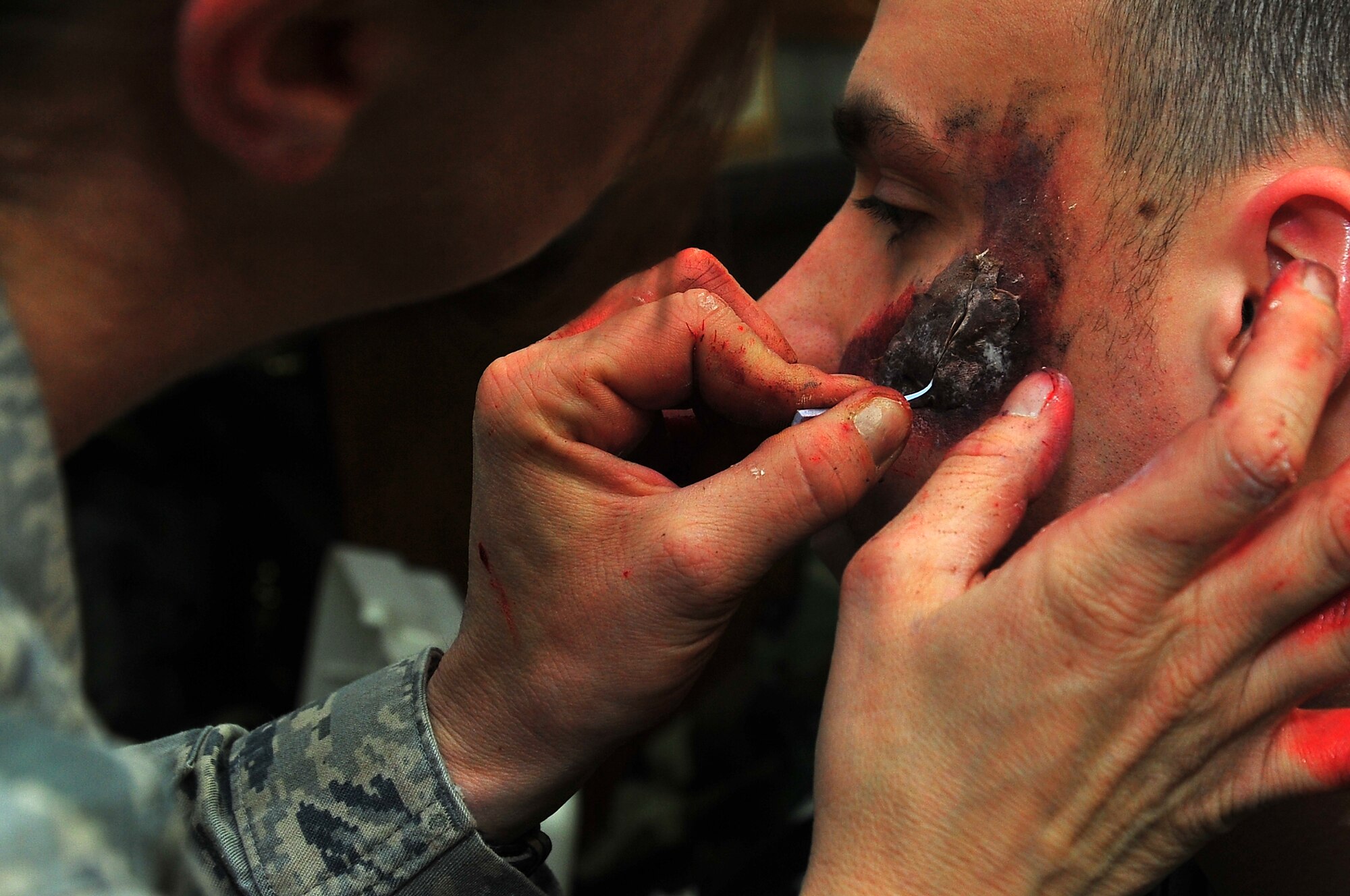 Senior Master Sgt. Tracey House, 51st Medical Support Squadron Superintendent, applies moulage to Senior Airman Kory Maurer, 51st Vehicle Maintenance mechanic, to simulate a head injury before a mass casualty simulation in building 1097 on Osan Air Base, Republic of Korea, Feb.13, 2013.  Moulage provides a sense of realism in exercises that medics and first responders may encounter in real-world accidents.  (U.S. Air Force photo/Staff Sgt. Emerson Nuñez)