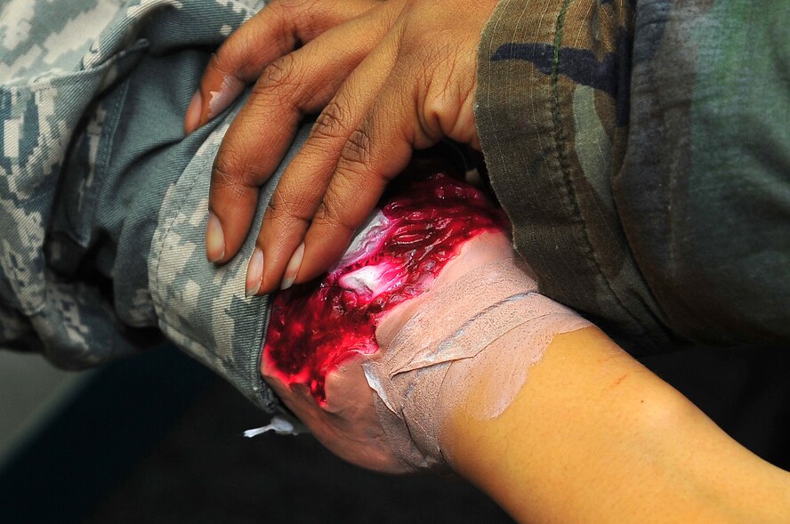 Major Charnell Smith, 51st Medical Support Squadron, applies moulage to  Airman 1st Class Devanee Lucero, 51st Munitions Squadron munitions technician in order to simulate an arm injury before a mass casualty simulation for operation readiness exercise Beverly Bulldog 13-02 in building 1097 on Osan Air Base, Republic of Korea, Feb. 13, 2013.  Moulage adds a more realistic training environment for first responders. (U.S. Air Force photo/Staff Sgt. Emerson Nuñez)