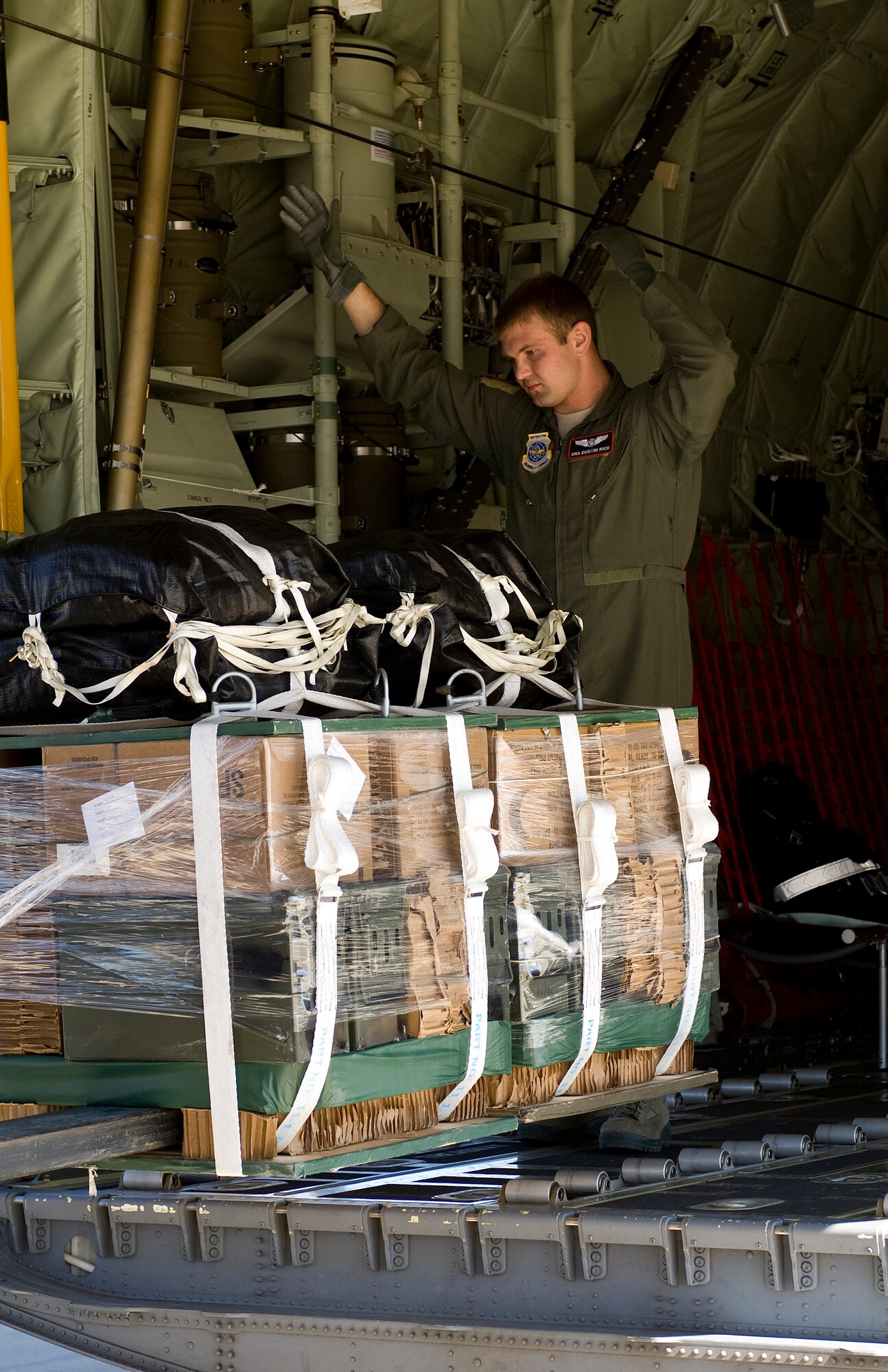 Senior Airman Dustin Rice, 39th Airlift Squadron, loads a low-cost-low-altitude bundle onto a 317th Airlift Group C-130J Feb. 7, 2013 at Fort Hood, Texas. The LCLA are a special bundles delivery system, designed to be used and discarded rather than turned in and reused.  This method saves the receiver trouble, and the low altitude helps with accuracy and staying under the radar of the enemy. (U.S. Air Force photo by Airman 1st Class Kylsee Wisseman/Released)