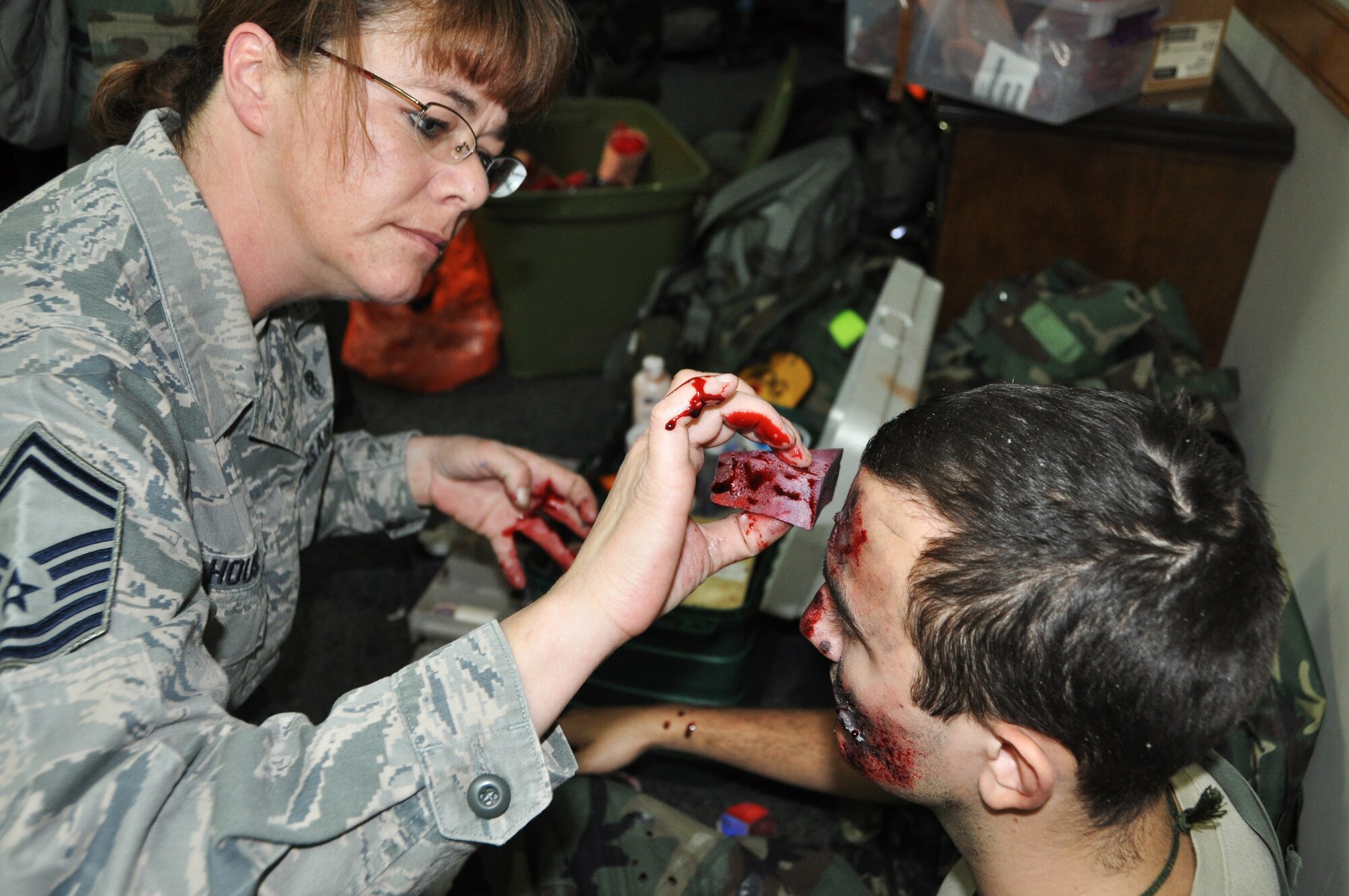 Senior Master Sgt. Tracey House, 51st Medical Support Squadron superintendent, applies fake blood to Airman 1st Class Peter Grenier, 51st Munitions Squadron munitions handler, for operational readiness exercise Beverly Bulldog 13-02, Feb. 13, 2013 at Osan Air Base, Republic of Korea.  Moulage is applied during the exercise to provide a more realistic scenario for Osan Airmen to practice self-aid buddy care during wartime conditions.  (U.S. Air Force photo/Senior Airman Kristina Overton)