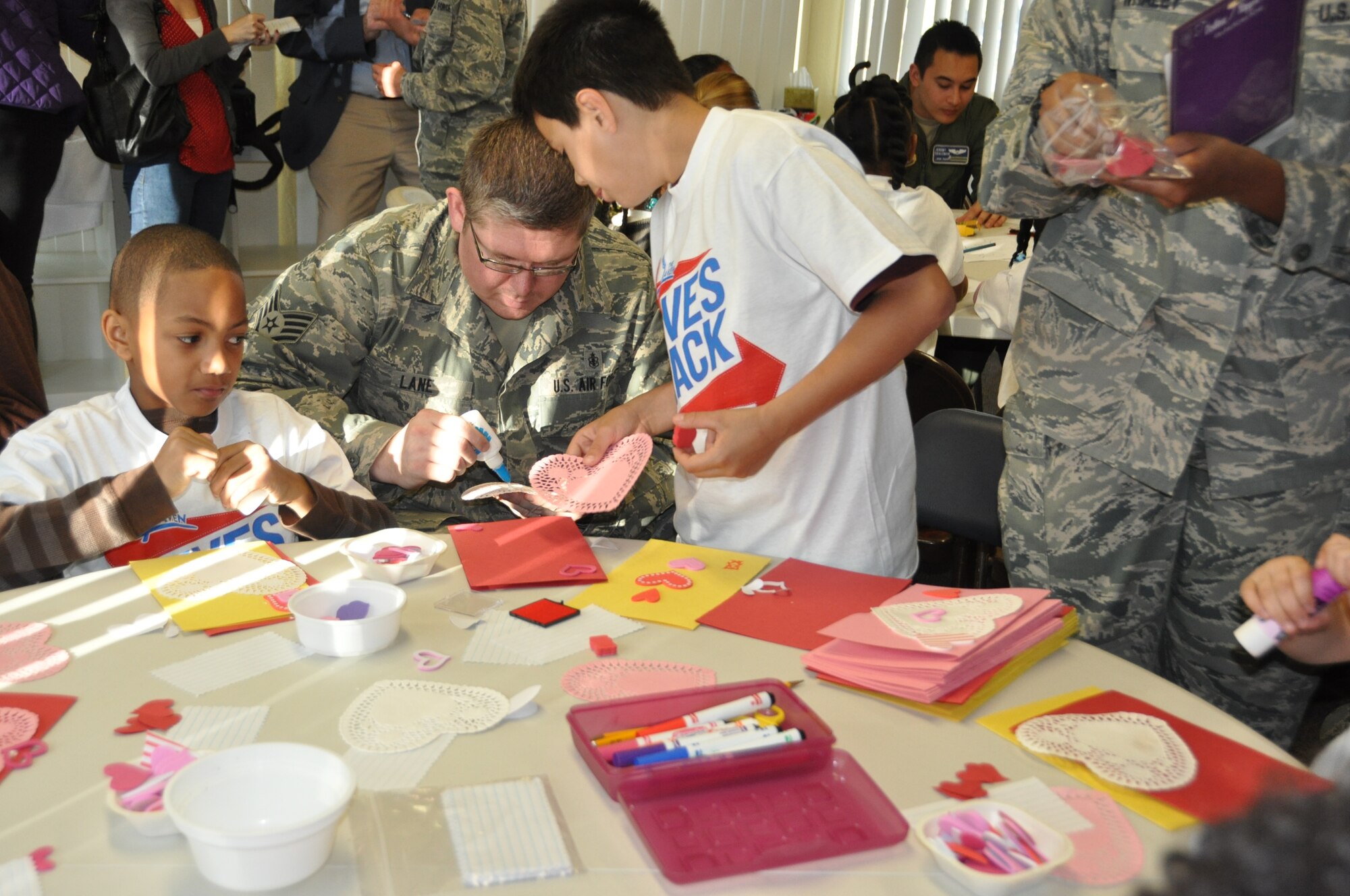 Staff Sgt. George Lane, 60th Diagnostics and Therapeutics Squadron, helps children  make Valentine's Day cards for deployed service members Feb. 7 at the Leaven in Suisun City (U.S. Air Force photo/Tyler Grimes)