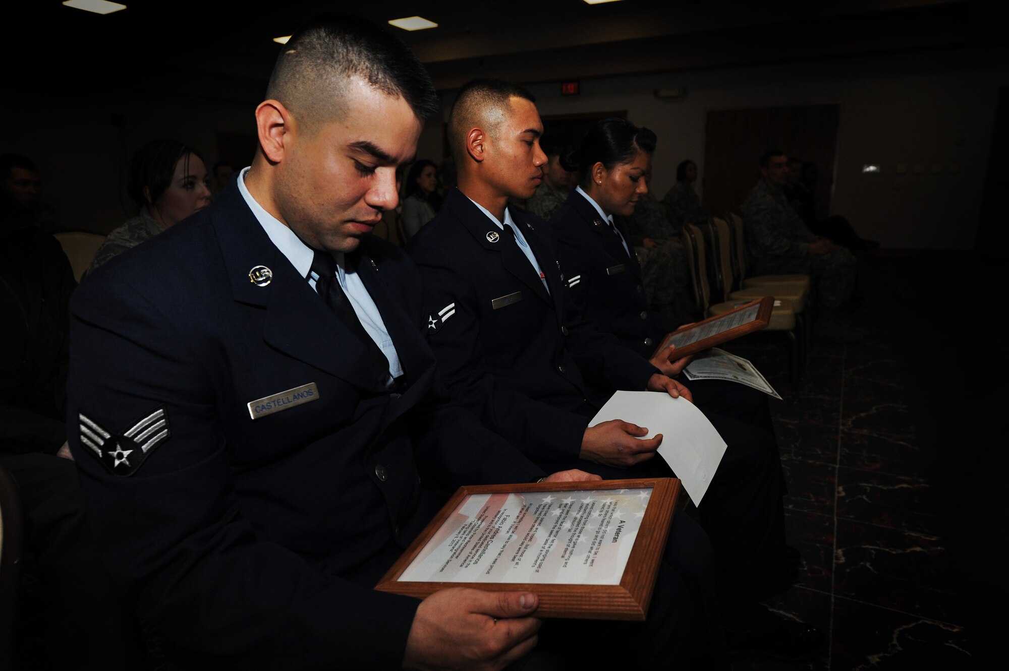 U.S. Air Force Airman 1st Class Fabio Castellanos and Airman 1st Class Mike Waga, 27th Special Operations Civil Engineer Squadron, and Airman 1st Class Maria Guerrero, 27th Special Operations Force Support Squadron, read a plaque describing the role of a veteran during a citizenship ceremony at Cannon Air Force Base, N.M., Feb. 8, 2013.  After serving active duty for a year in the U.S. Air Force during a time of war, the Airmen were able to apply for naturalization. (U.S. Air Force photo/Senior Airman Jette Carr)