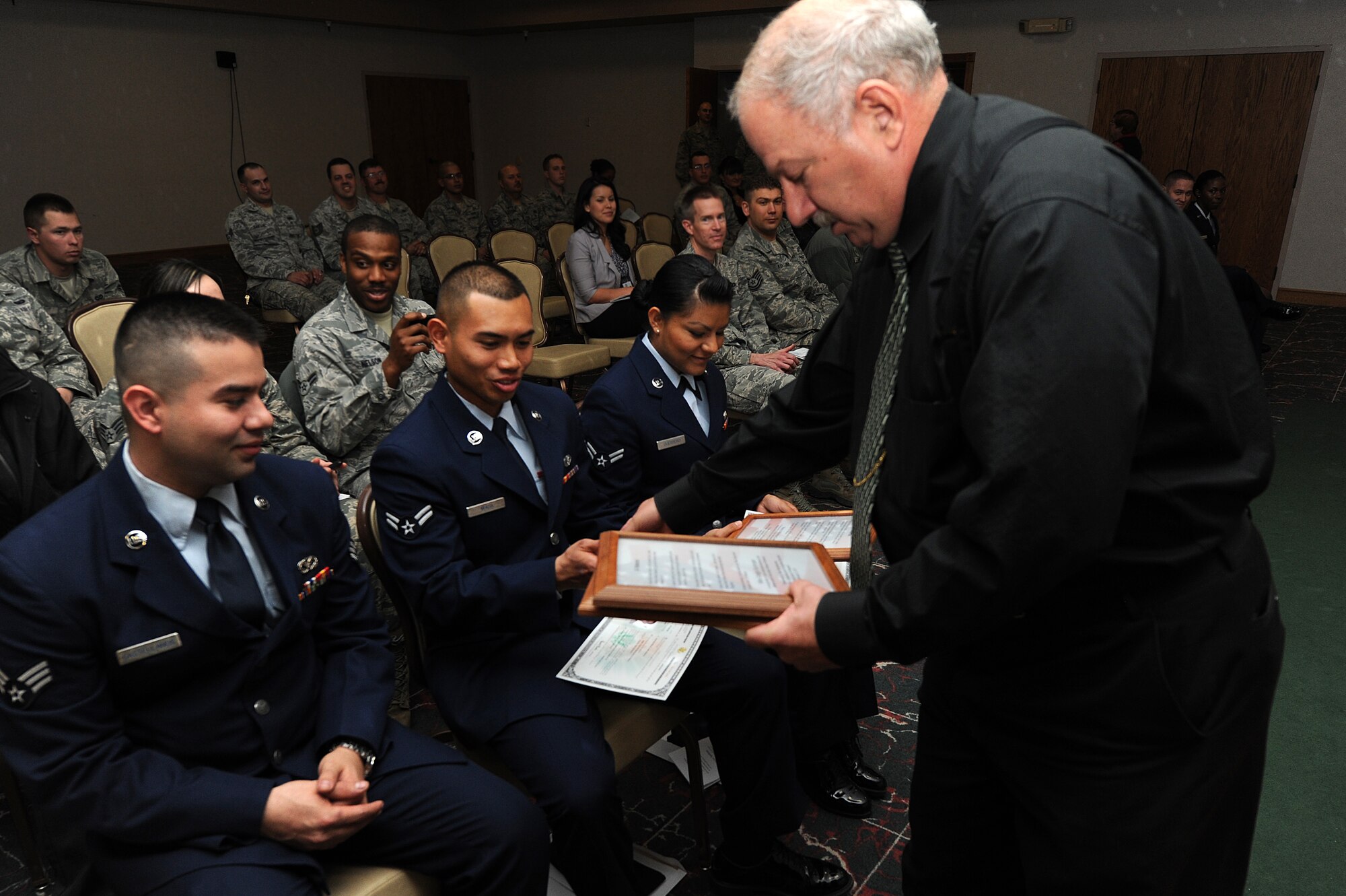 Peter Rechkemmer, United States Citizenship and Immigration Services officer, awards three Air Commandos with their certificates of naturalization and plaques describing the role of a veteran during a citizenship ceremony at Cannon Air Force Base, N.M., Feb. 8, 2013. After serving active duty for a year in the U.S. Air Force during a time of war, the Airmen were able to apply for U.S. citizenship. (U.S. Air Force photo/Senior Airman Jette Carr)