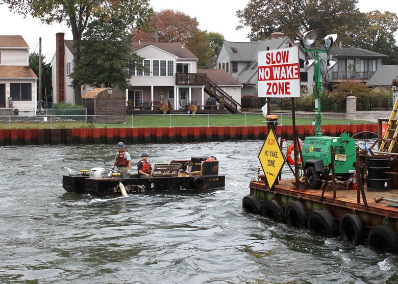 Contractors from Abhe & Svoboda Inc. approach a barge along the Point Pleasant Canal bulkhead during a repair project. On both sides of the canal, the steel sheet-pile bulkhead protects development. The U.S. Army Corps of Engineers Philadelphia District is working to repair the bulkhead with innovative techniques rather than replace it.  