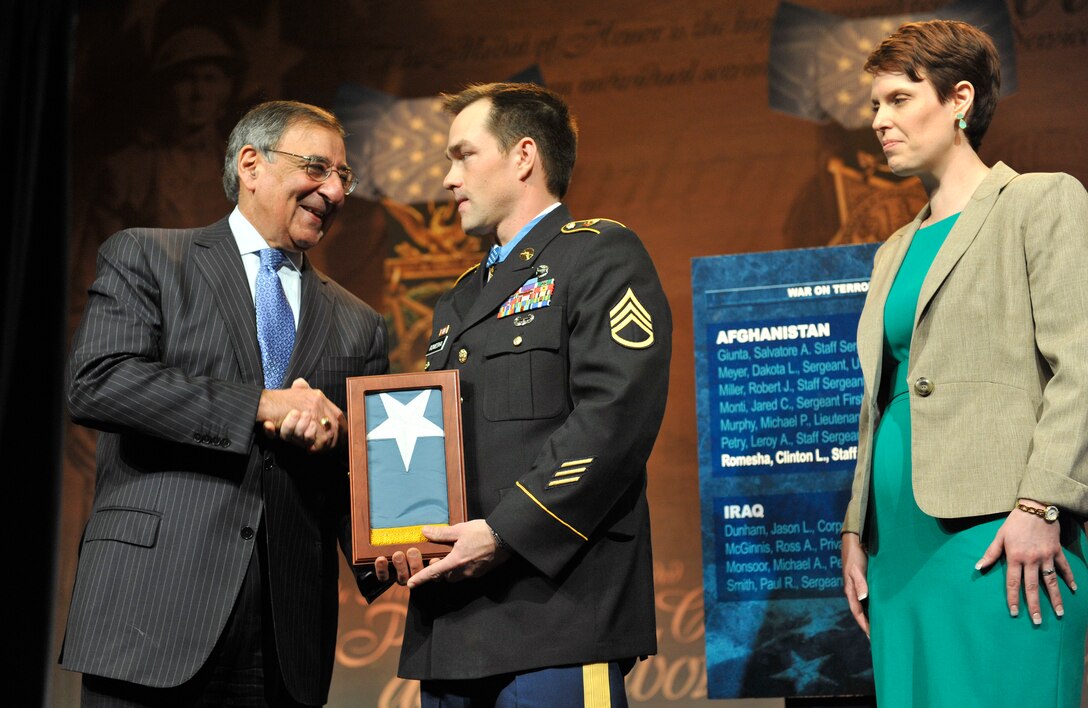 Defense Secretary Leon E. Panetta presents former Army Staff Sgt. Clinton L. Romesha with the Medal of Honor Flag at the Pentagon, Feb. 12, 2013, as his wife, Tamara, looks on.