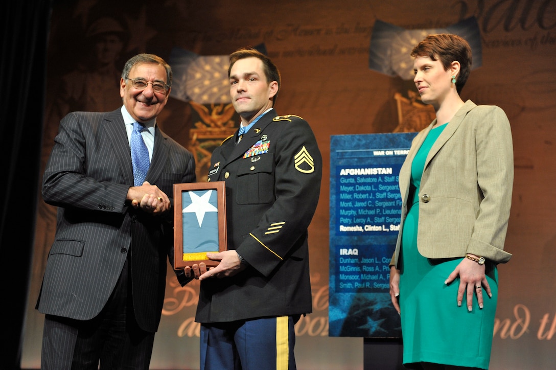 Defense Secretary Leon E. Panetta presents former Army Staff Sgt. Clinton L. Romesha with the Medal of Honor Flag at the Pentagon, Feb. 12, 2013, as his wife, Tamara, looks on.