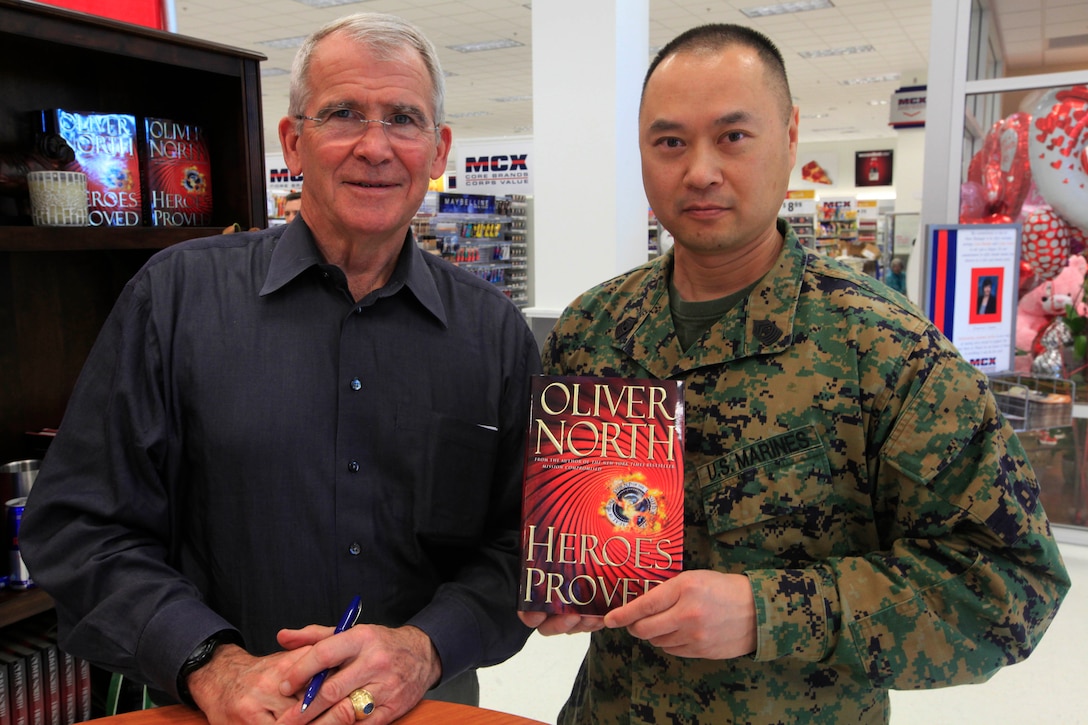 Best-selling author, retired Lt. Col. Oliver North, left, stand with Master Gunnery Sgt. Hon Loung, right, the G-6 communications chief for 1st Marine Logistics Group, during a book signing event here Feb. 12. Since North's military retirement, he has written best-selling books including American Heroes in Special Operations, Mission Compromised, The Jericho Sanction and American Heroes: In the Fight Against Radical Islam.