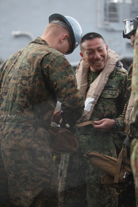 ABOARD USS PEARL HARBOR (LSD-52).- Lance Cpl. Windinhair Gilland, a South Saltillo, Miss. native and combat cargo crewman with USS Pearl Harbor (LSD-52), assists a member of the Western Army Infantry Regiment, Japan Ground Self Defense Force with his life preservation unit as he prepares to insert onto San Clemente Island, Calif., for training during Exercise Iron Fist 2013, Feb.8, 2013. During Exercise Iron Fist 2013, the 13th Marine Expeditionary Unit and JGSDF will spend three weeks participating in bilateral training to improve their interoperability, enhance military-to-military relations, and sharpen skills essential to crisis response.  (U.S. Marine Corps photo by Sgt. Christopher O’Quin/Released)
