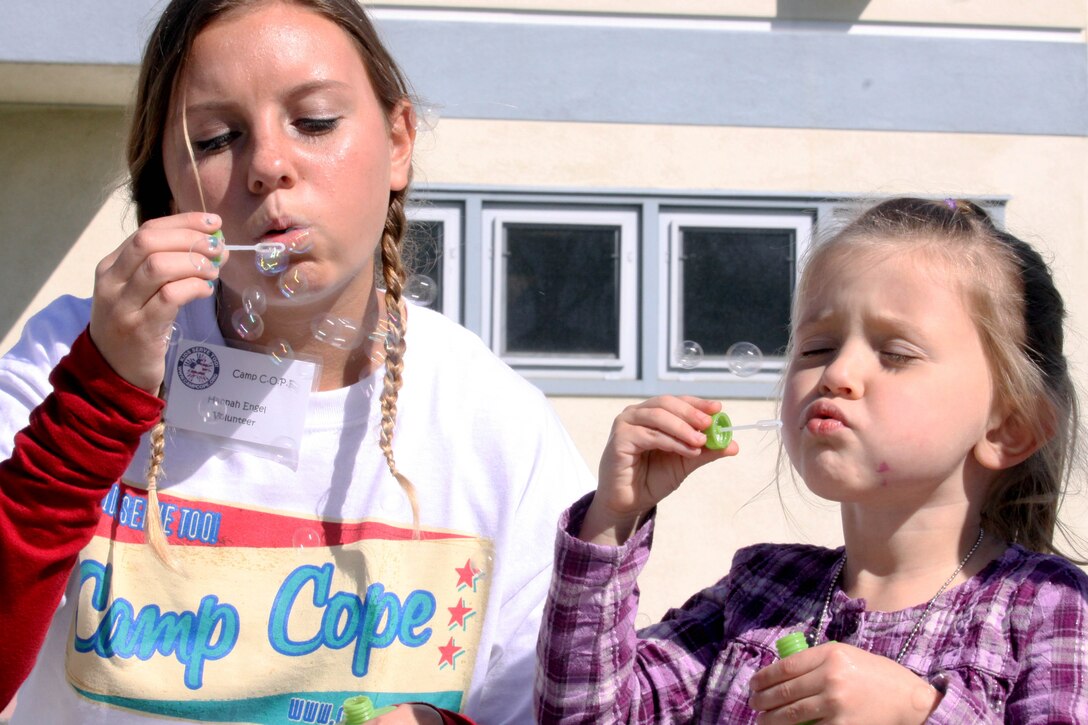 Hannah, a 15-year-old volunteer for Camp C.O.P.E., left, and Amelia, 4, practice deep breathing techniques by blowing bubbles during the camp held at Stuart Mesa Elementary School here Feb. 9. The camp's focus is to teach children new ways to cope with a parent's injury or deployment.
