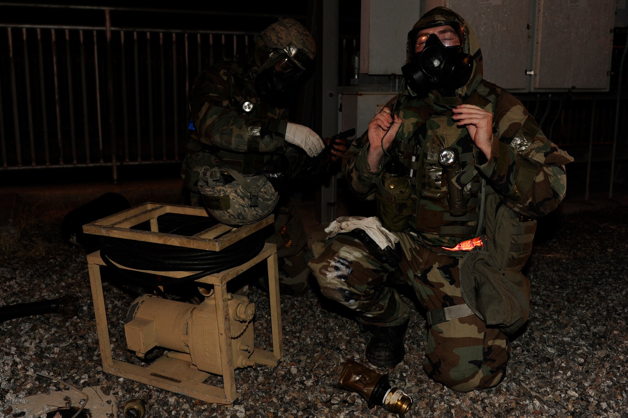 Senior Airman Marvin Carter, left, and Senior Airman Jeremy Robinson, 8th Civil Engineer Squadron, change to MOPP 2 after being given the  instruction during exercise Beverly Bulldog 13-2 at Kunsan Air Base, Republic of Korea, Feb. 13, 2013. The Airmen were setting up a reverse-osmosis, water-purification system to supply safe drinking water for the base. contamination. (U.S. Air Force photo by Senior Airman Marcus Morris/Released)