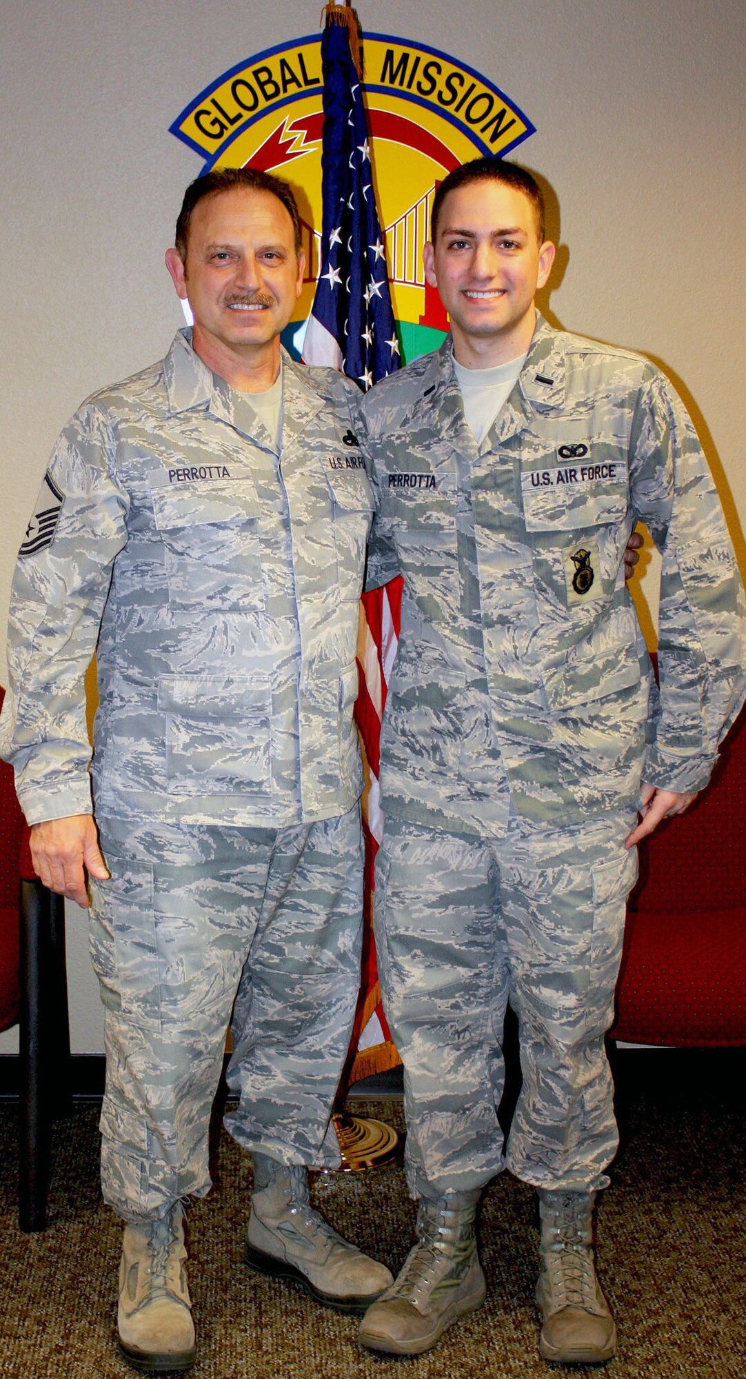 TRAVIS AIR FORCE BASE, Calif. -- Dad, Master Sgt. Camillo C. Perrotta, Sr., strikes a proud pose with his son, 1st Lt. Camillo C. Perrotta, Jr. Perrotta, Jr., flew out to Travis all the way from his duty station of Minot AFB, N.D., to reenlist his father for his next to last time, in the U.S. Air Force Reserve. They plan to reunite for Dad's last enlistment, and for the lieutenant to hopefully, preside over Perrotta, Sr.'s retirement ceremony as well. (Courtesy photo)(Courtesy photo)