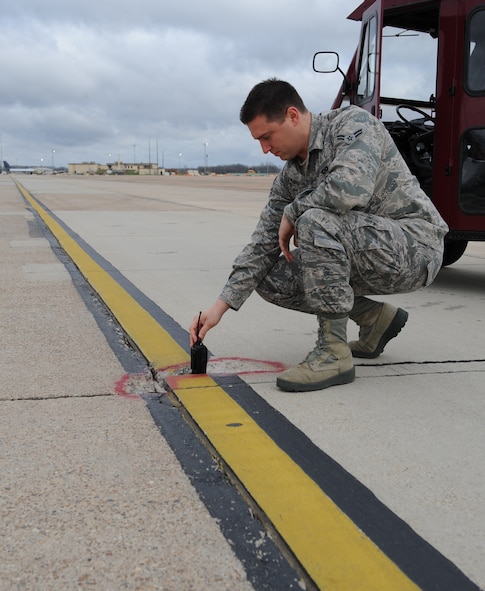 Airman 1st Class Andrew Henggeler, 2nd Operations Support Squadron airfield management, checks the depth of a hole in the pavement on the flightline at Barksdale Air Force Base, La., Feb. 13. Airfield management ensures safe operations of aircraft, personnel and vehicles on the airfield. (U.S. Air Force photo/Airman 1st Class Benjamin Gonsier)