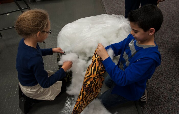 Danyelle Gibson, daughter of Tech. Sgt. Robert Alvarado, 437th Aircraft Maintenance Squadron communications and navigation systems craftsman, and Matthew Hughes, stepson of Sgt. Luis Crovetto, Marine Corps Reserve Unit heavy equipment chief, stuff pillows Feb. 12, 2013, at the Joint Base Charleston- Air Base Youth Program. 'Pillows for Troops' is an ongoing project at the Youth Program Center, where children ages 9 to 15 are able to make pillows for troops who are deployed overseas. The project takes place every Tuesday through Friday from 3:30 p.m. to 4:30 p.m. (U.S. Air Force photo/Airman 1st Class Ashlee Galloway)