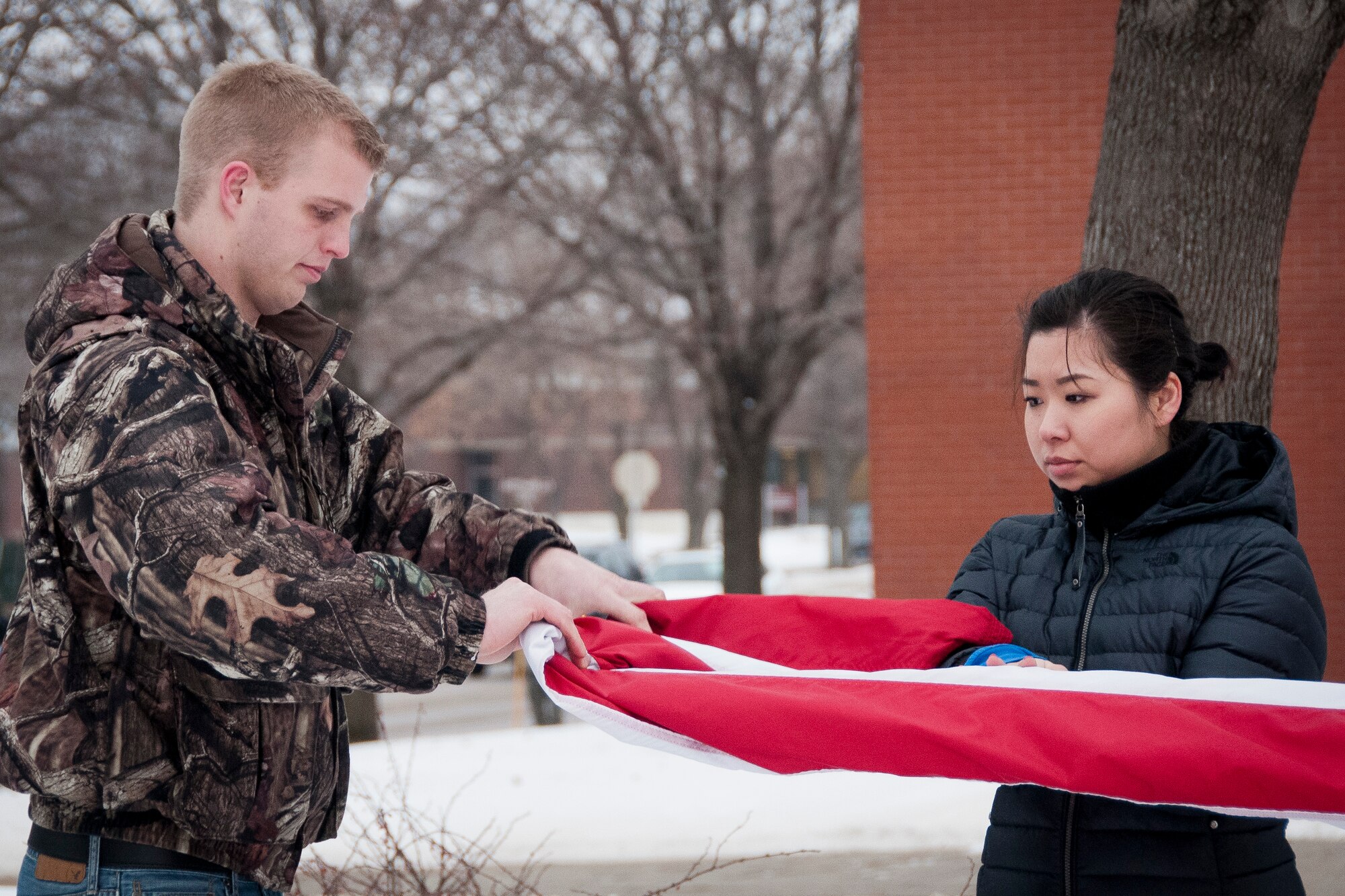 Luke Miller folds the flag while being assisted by Sarah Pearson.  Members from the 934th Airlift Wing Development Training Flight were tasked to lower the flags during the retreat ceremony at the end of the duty day on Feb. 9 at the Minneapolis-St. Paul Air Reserve Station, Minn. (U.S. Air Force photo/Staff Sgt. Samantha Wagner)