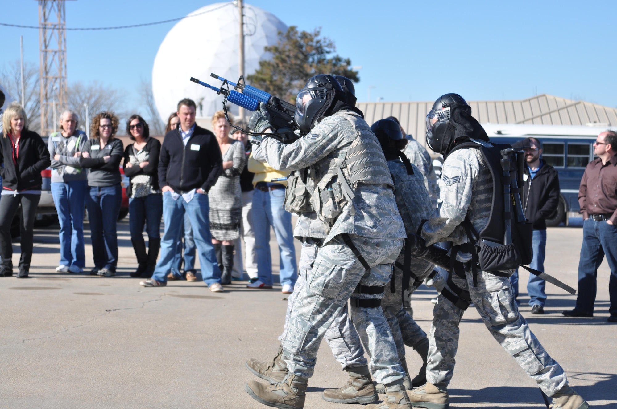 Members of Leadership Sarpy watch as four 55th Security Forces Squadron members approach the shoot house in a diamond formation during an active shooter demonstration on Feb. 5. (U.S. Air Force Photo by 2nd Lt. Carly Costello/Released)