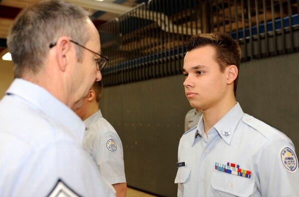 Julian Kandt (right), Douglas High School Air Force junior ROTC cadet, stands at attention while retired Chief Master Sgt. Russell Johnson (left), Douglas High School Air Force junior ROTC aerospace science instructor, inspects his uniform during an open ranks inspection at Douglas High School in Box Elder, S.D., Feb. 11, 2013. Kandt is a member of Bravo flight, and like all the other cadets must wear one uniform combination on the first day of the week. (U.S. Air Force photo illustration by Airman Ashley J. Thum/Released)