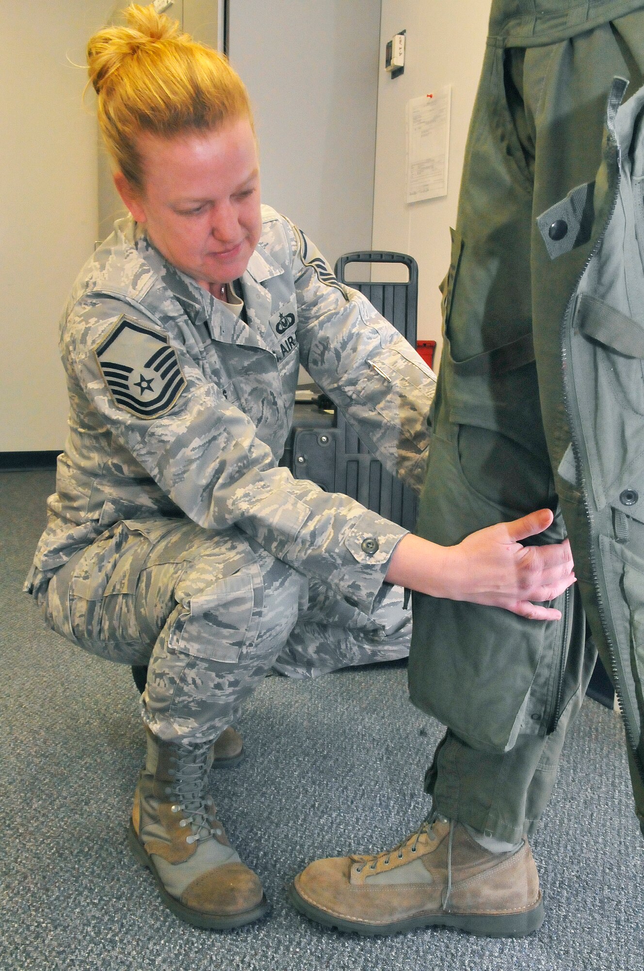 Master Sgt. Sara Glass, aircrew flight equipment technician, demonstrates how Anti-G suits are worn.The suits are custom fit and blow air to keep circulation moving so the pilot doesn't pass out while pulling Gs. (U. S. Air Force photo/Sue Sapp)