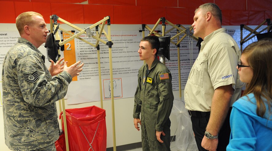 Tech. Sgt. Bryan Dickson, 15th Operations Support Squadron, aircrew flight equipment, explains the steps for decontaminating military personnel infected after a chemical attack, to Caleb Jensen, his father Darwin and sister London as part of the Pilot for a Day program at Joint Base Pearl Harbor-Hickam, Hawaii, Feb. 8, 2013. Pilot For a Day candidates are selected from military and civilian children in the local community suffering from a serious or terminal illness. (U.S. Air Force photo/Tech. Sgt. Jerome S. Tayborn)