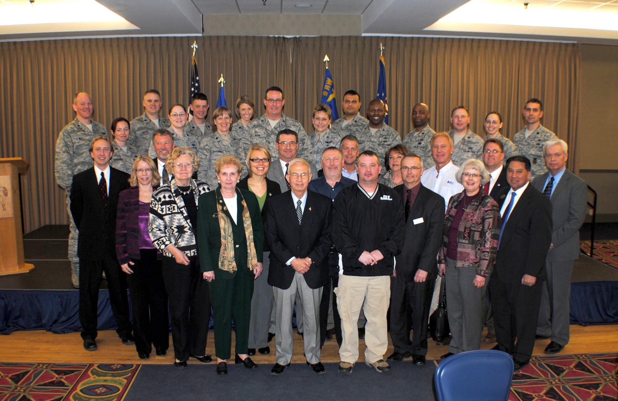 Grand Forks Air Force Base commanders, base ambassadors and honorary commanders take to the stage for a group photo to commemorate the installation’s 2013 Honorary Commander Induction Ceremony on Feb. 8, 2013 at the Northern Lights Club on Grand Forks AFB, N.D. (U.S. Air Force photo/Senior Airman Luis Loza Gutierrez)
