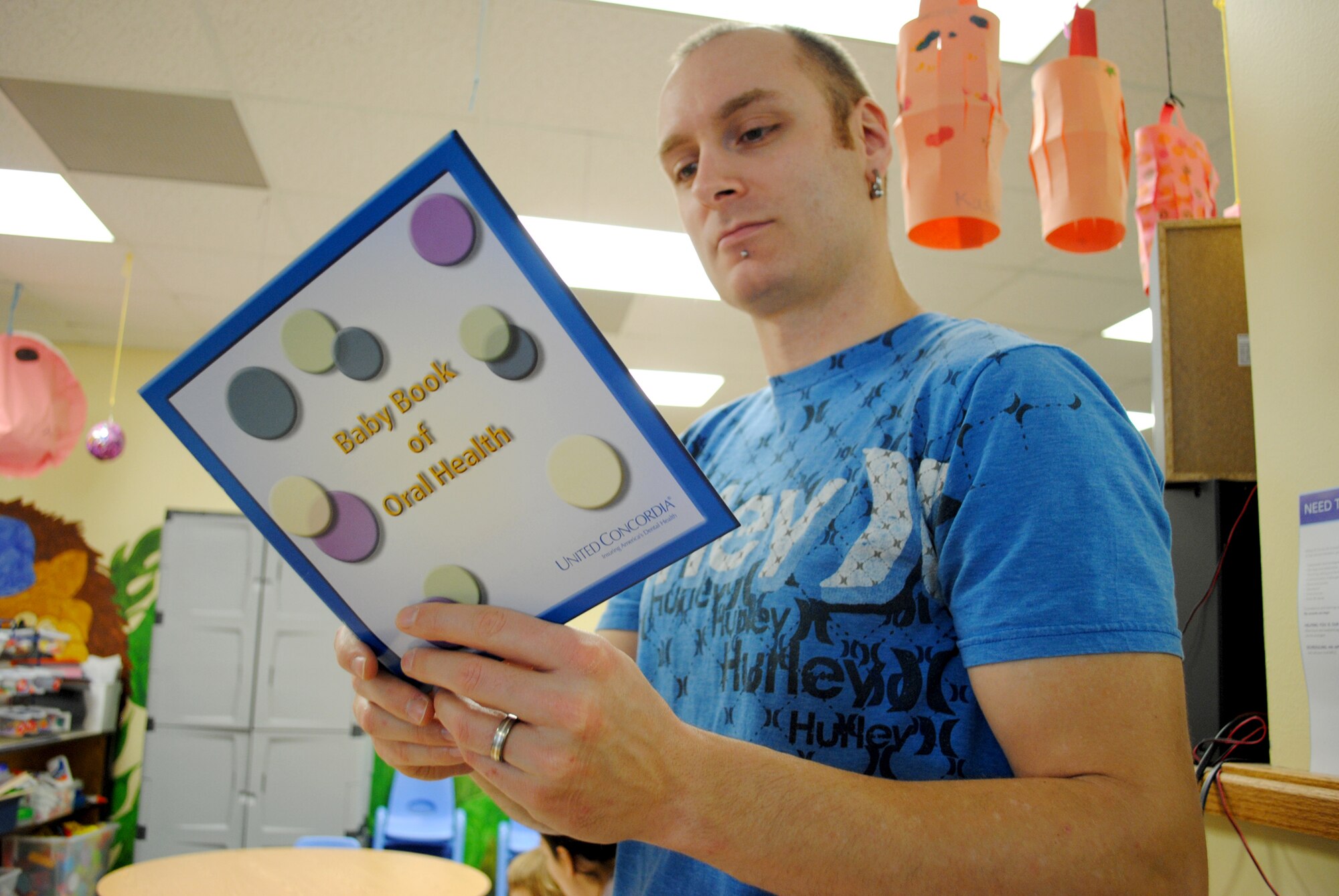 Jesse Teale, Air Force spouse, cracks open a copy of a book titled, “Baby Book of Oral Health,” during a visit by three base dental health experts to the Parent Child Center on Grand Forks Air Force Base, N.D. , on Feb. 12, 2013. The book was one of the informational items provided to parents during the visit, which was conducted in observance of National Children's Dental Health Month, a nation-wide campaign endorsed by the American Dental Association designed to promote awareness about the importance of oral health. (U.S. Air Force photo/Senior Airman Luis Loza Gutierrez)