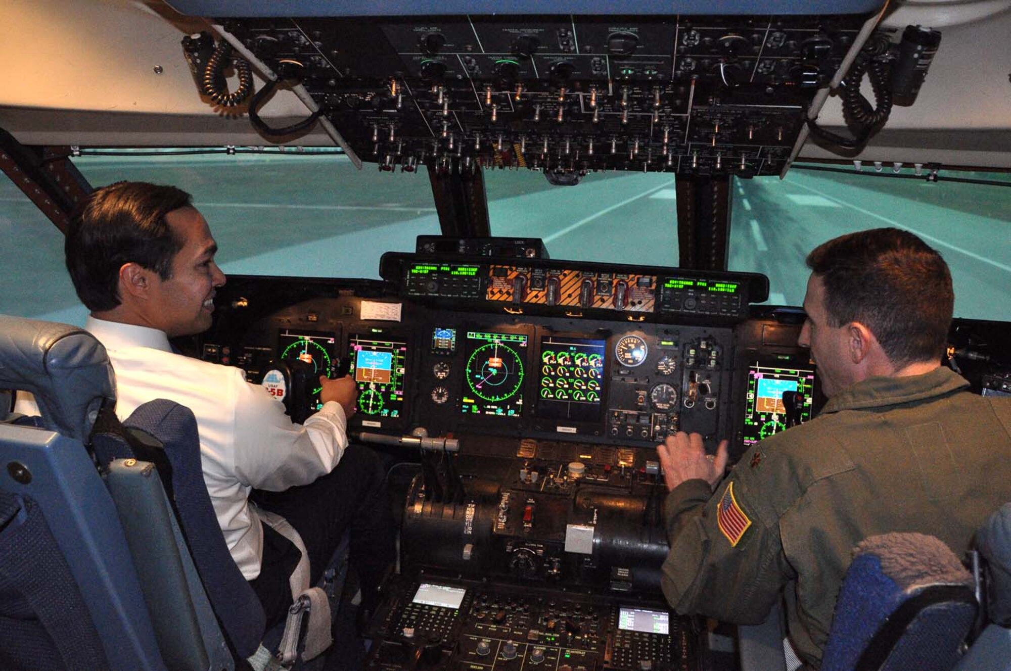 The Honorable Julian Castro, mayor of San Antonio,"pilots" a C-5A Galaxy Formal Training Unit’s flight simulator. Maj. Steve Radtke 433rd Operations Support Squadron, "trains" the mayor during his visit to the Alamo Wing Feb. 12, 2013. The unique “C-5 School House” operated by the 433rd Airlift Wing qualifies Active Duty, Guard, and Reserve aircrews on the C-5 weapon system. (U.S. Air Force photo by 1st Lt. Denise Haeussler) 
